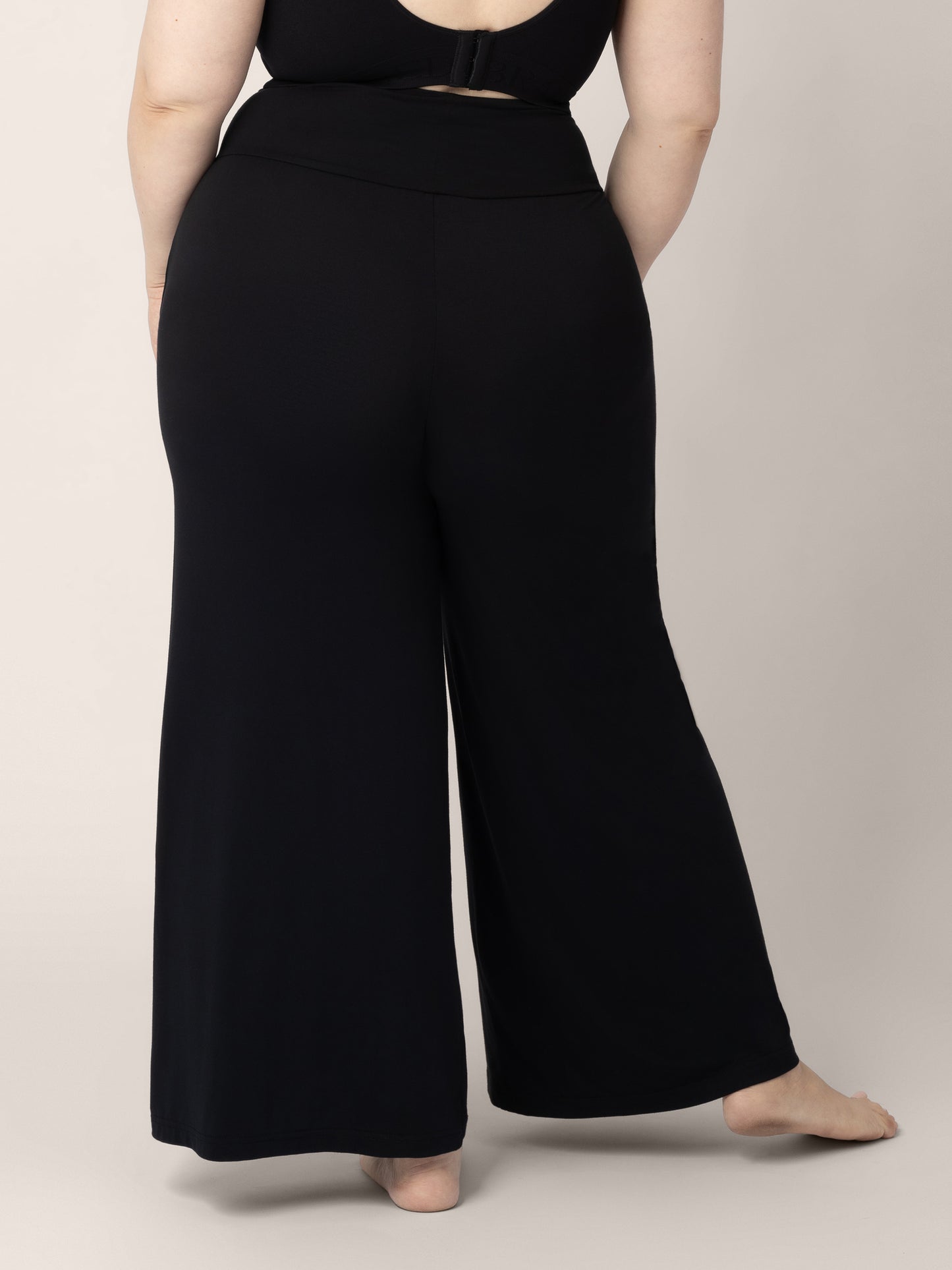 Back view of the bottom half of a pregnant model wearing the Bamboo Wide Leg Maternity & Postpartum Lounge Pant in Black 