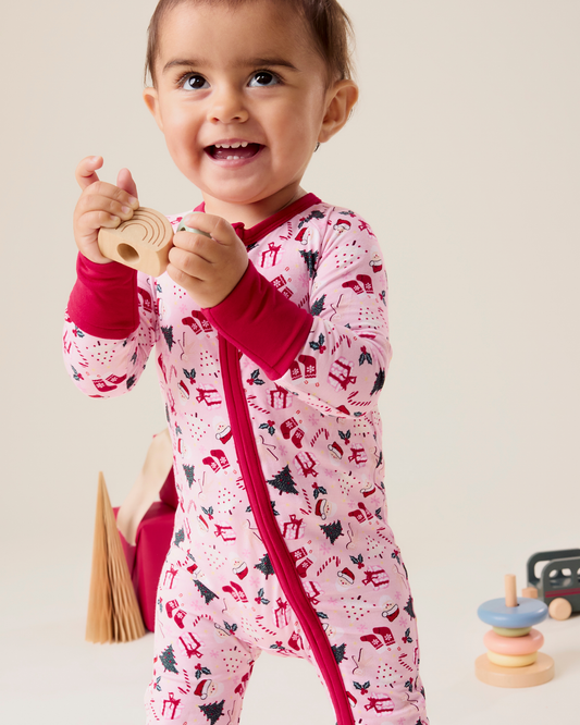 Baby wearing the Bamboo Baby Pajama in pink with holiday pattern and red trim@model_info:Delilah is wearing 3-6 months.