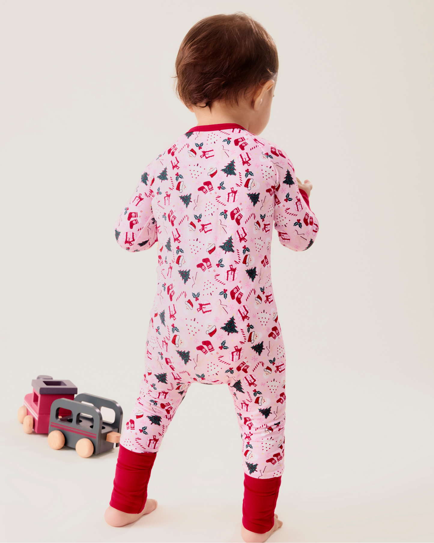 Baby wearing the Bamboo Baby Pajama in Candy Cane Lane - pink with holiday pattern and red trim