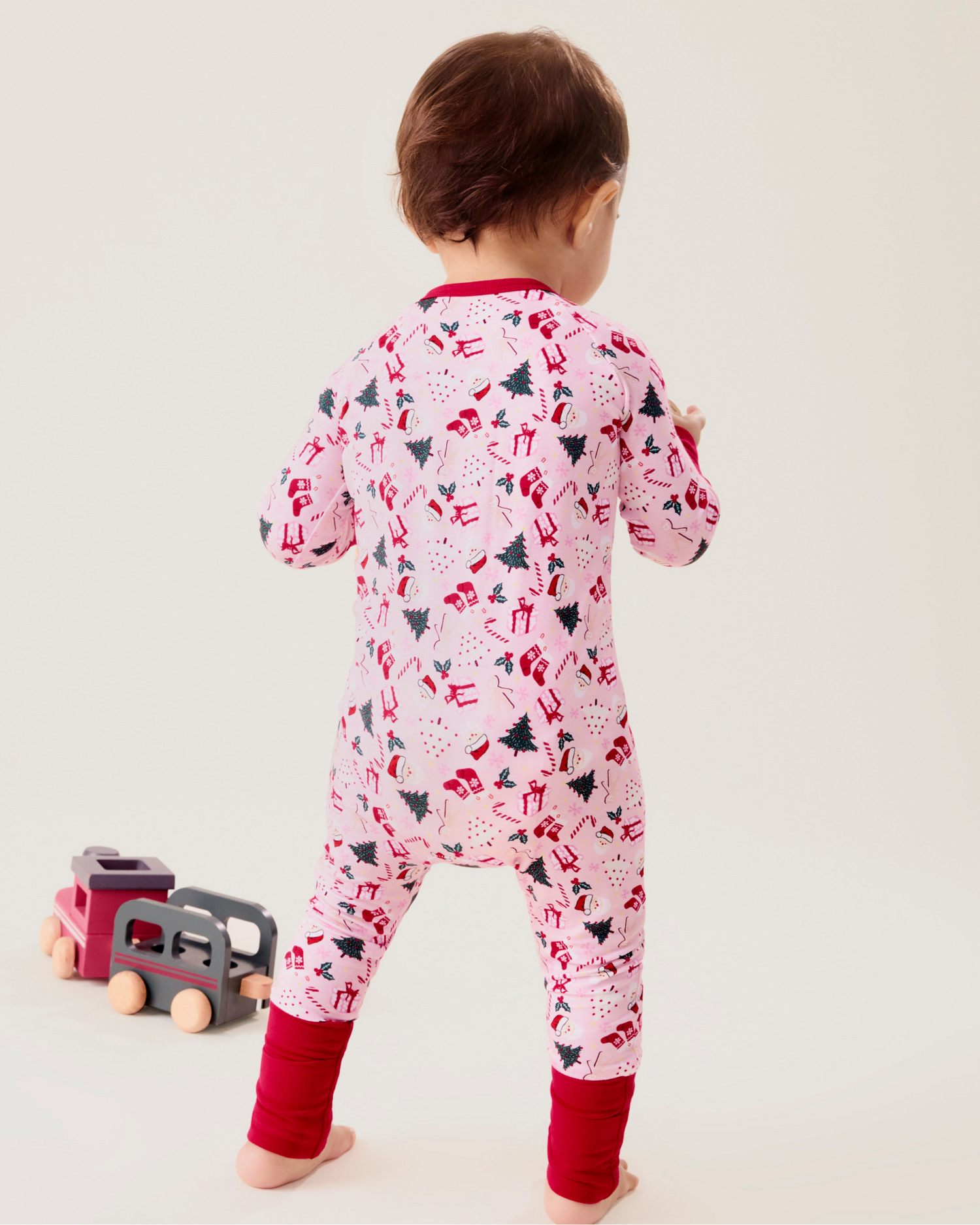 Baby wearing the Bamboo Baby Pajama in Candy Cane Lane - pink with holiday pattern and red trim