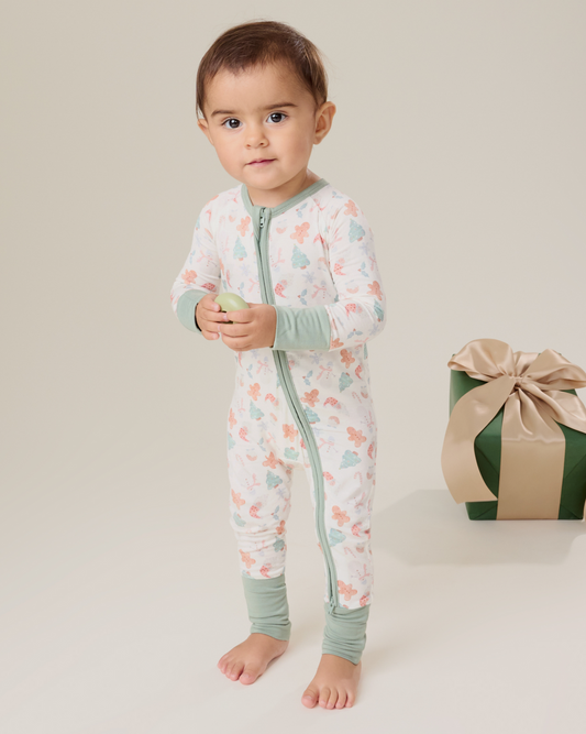Baby wearing the Bamboo Baby Pajama in Cozy Holiday pattern with soft light green trim@model_info:Delilah is wearing 3-6 months.