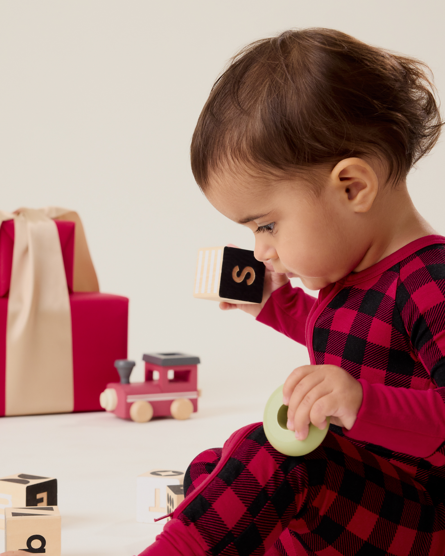 Baby sitting wearing the Bamboo Baby Pajama in Red Plaid and playing with blocks
