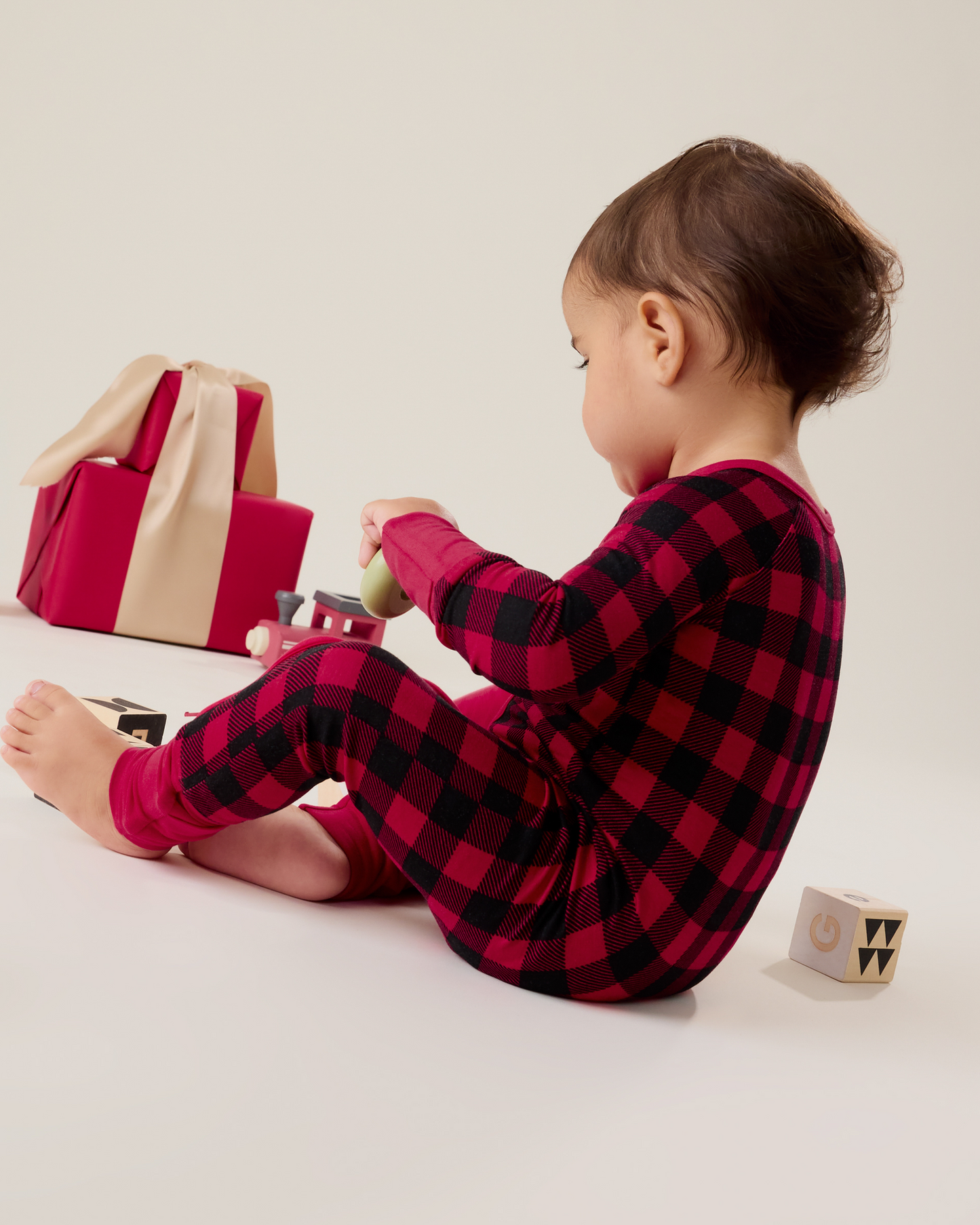 Baby sitting wearing the Bamboo Baby Pajama in Red Plaid