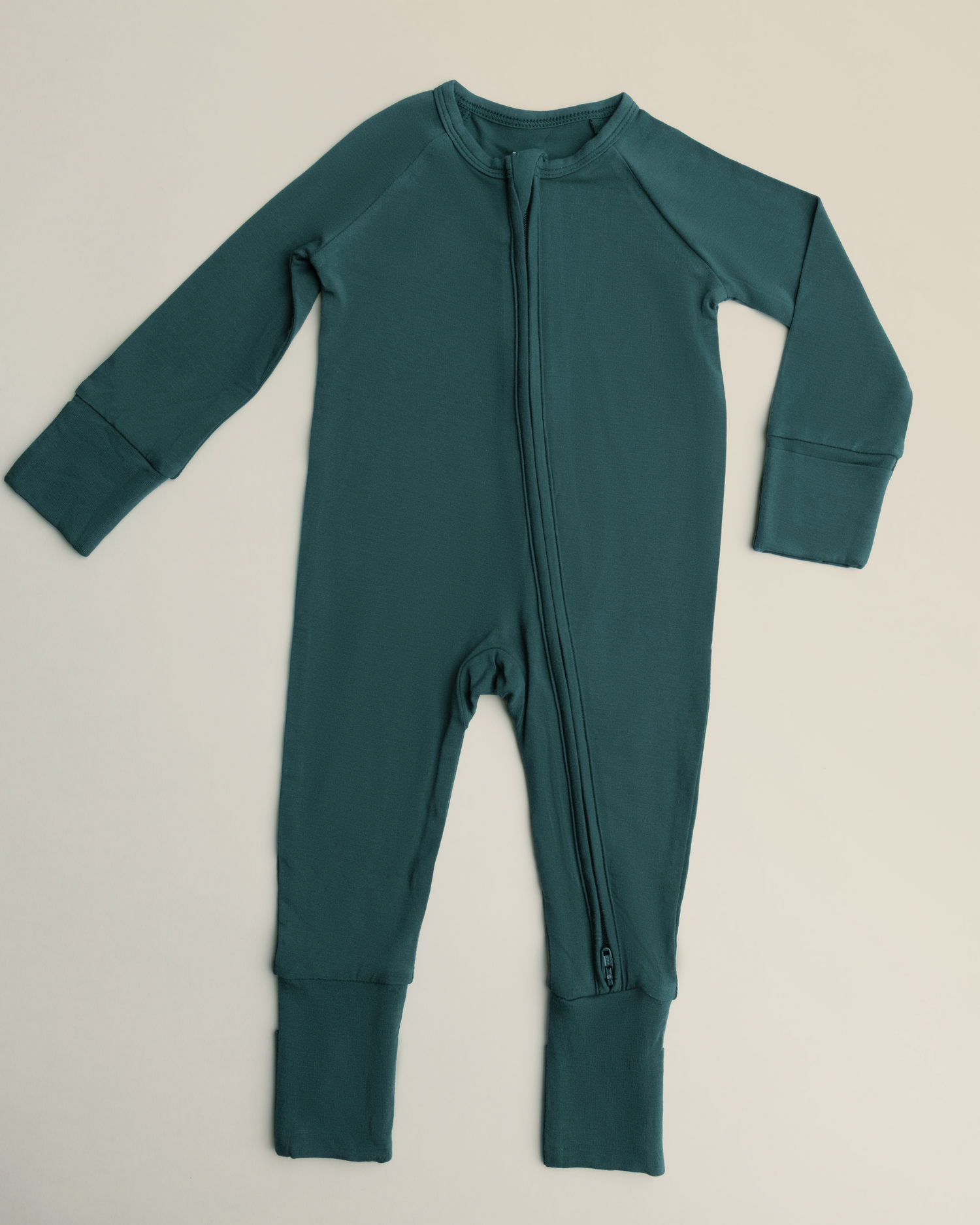 Bamboo Baby Pajamas in Evergreen with a zipper on a beige background