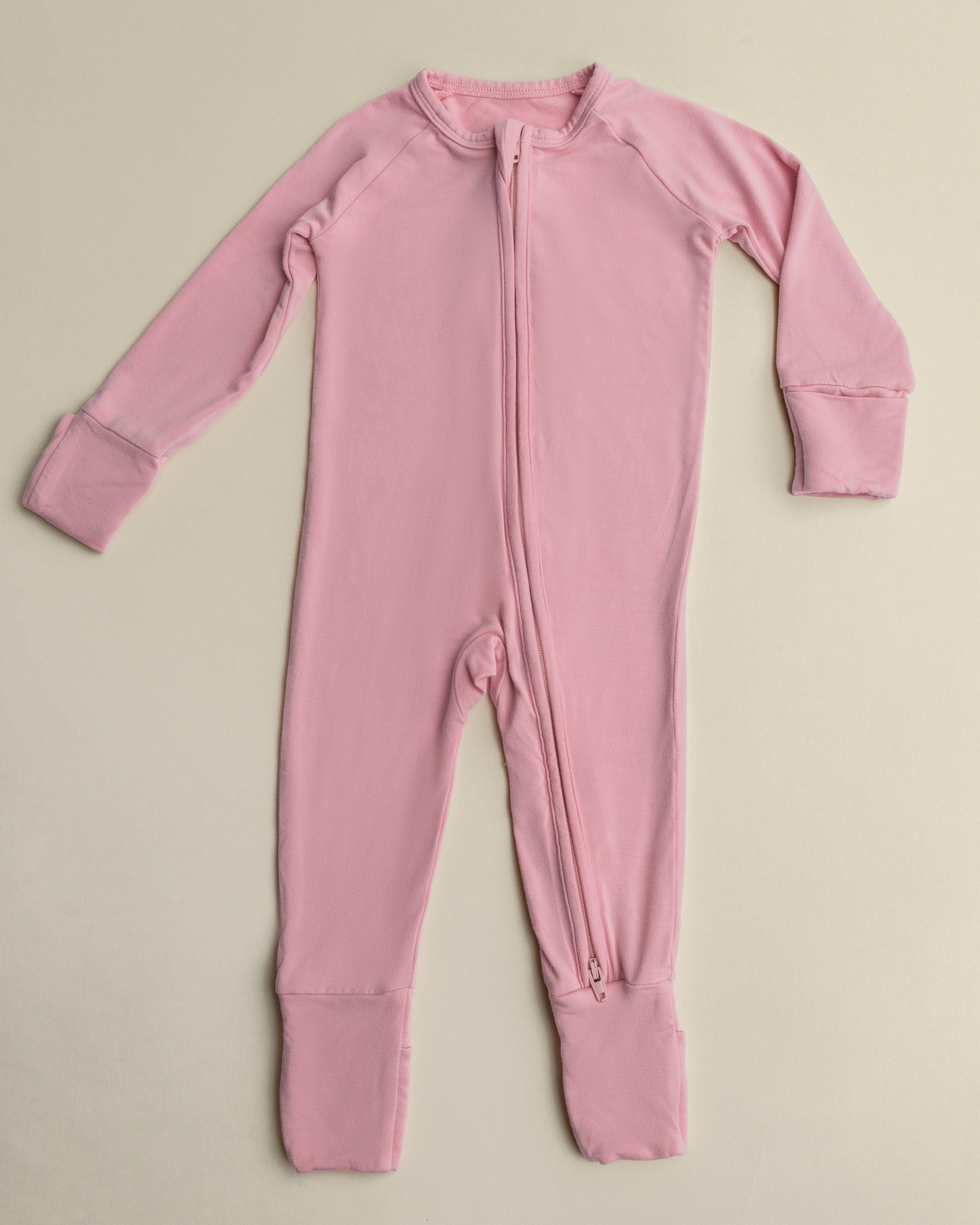 Bamboo Baby Pajamas in Light Mauve with a zipper on a beige background