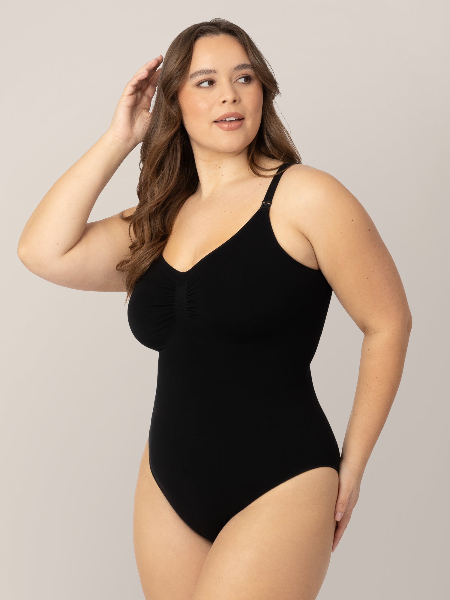 Model wearing the Sublime®️ Bamboo Maternity & Nursing Bodysuit in Black with one hand on her thigh and the other in her hair.  @model_info:Venezia is wearing a Large.