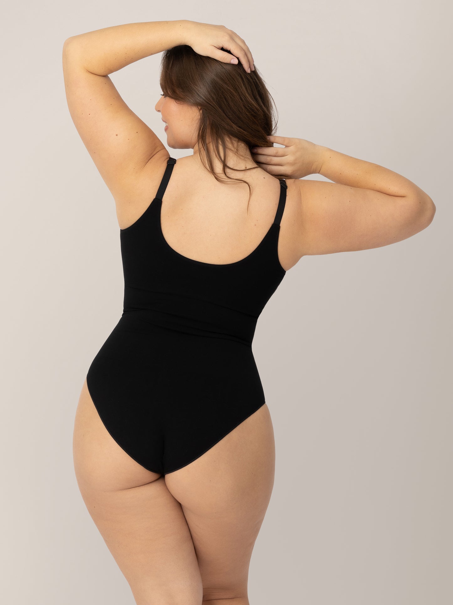 Back of a model wearing the Sublime®️ Bamboo Maternity & Nursing Bodysuit in Black with her hands in her hair. 