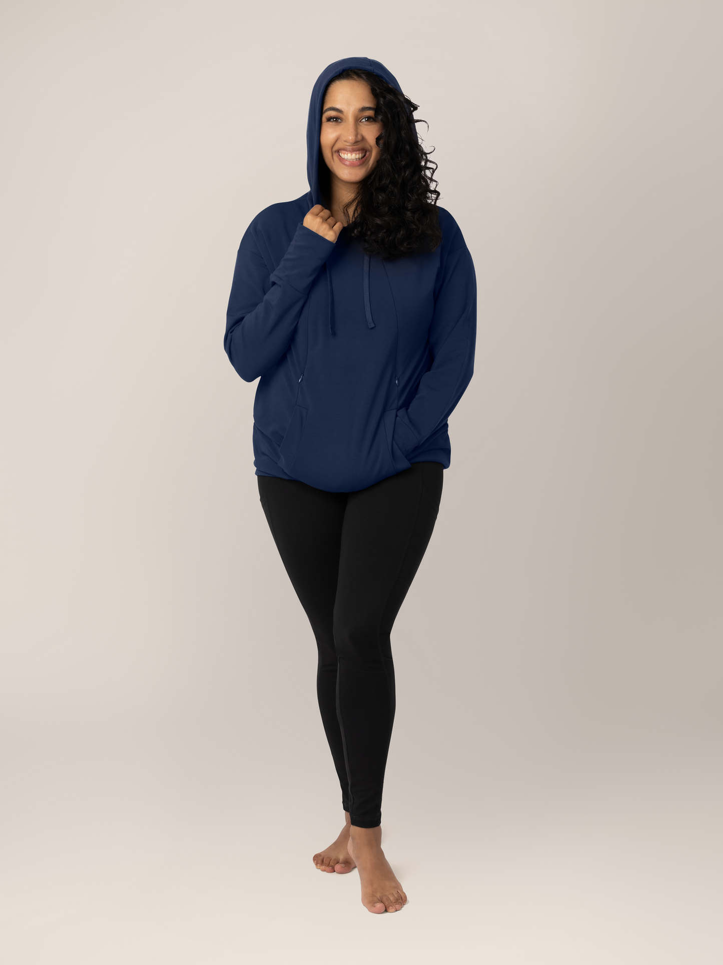 Model wearing the Bamboo Nursing Hoodie in Navy with her hand on the hood. @model_info:Zakeeya is wearing a Small.
