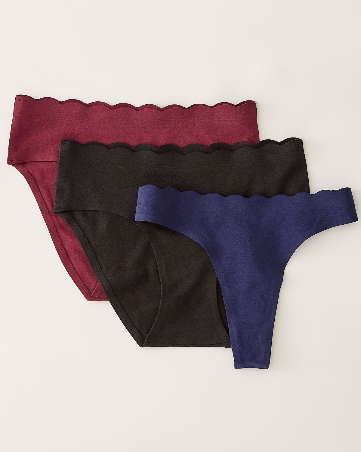 BareBond™ Cotton Maternity & Postpartum Brief in Garnet, Hipster in Black and Thong in Coastal Navy. Laid flat on a beige background.