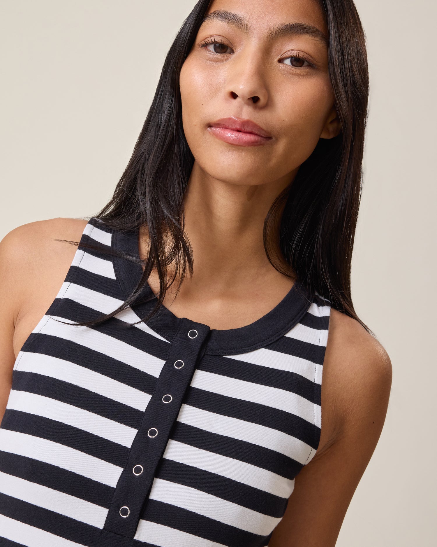 Woman wearing the Charlotte Mixed Media Nursing Midi Dress, showing the black & white striped top with buttons on a beige background