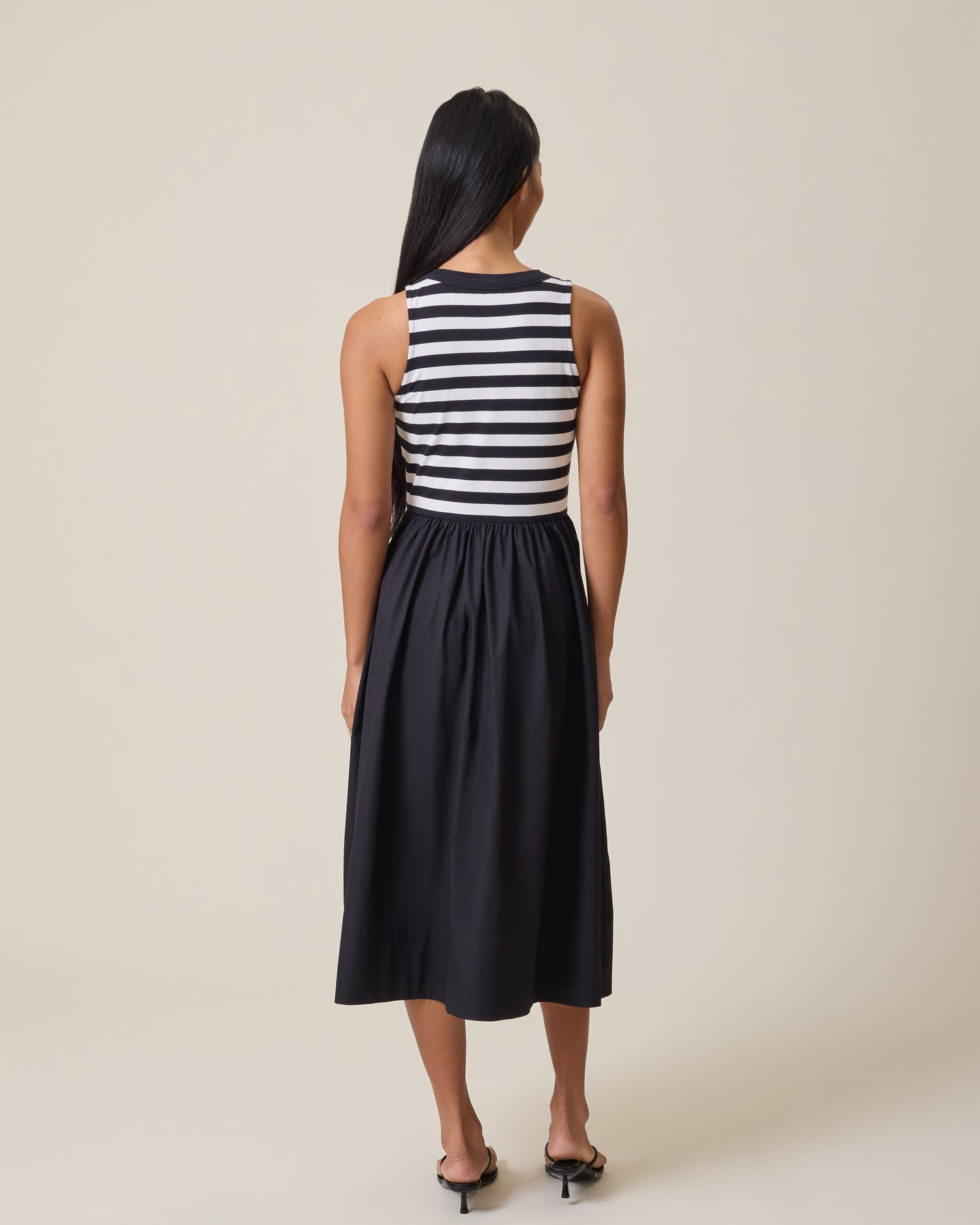 Woman wearing Charlotte Mixed Media Nursing Midi Dress with black & white striped top and black skirt on a beige background