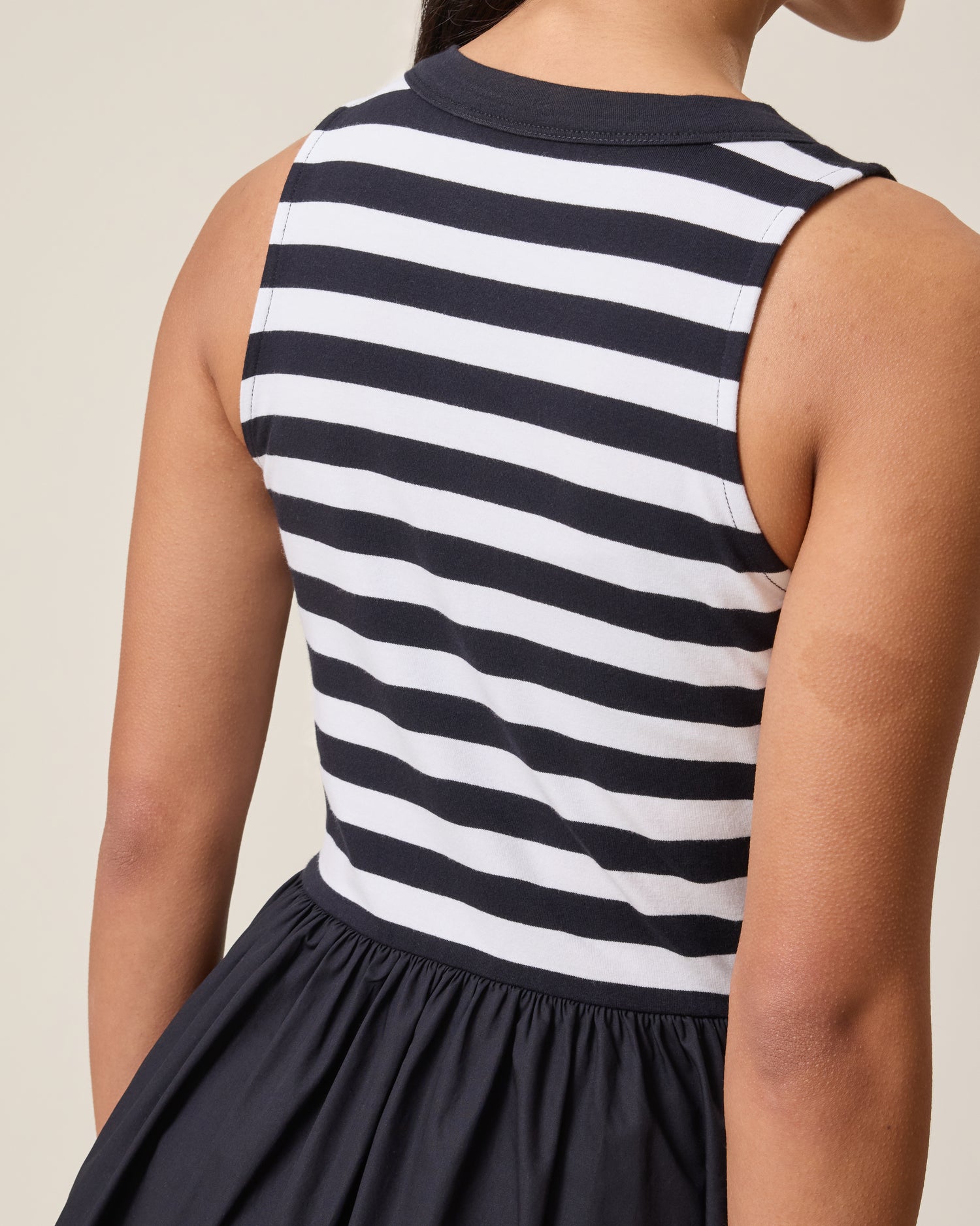 Woman wearing the Charlotte Mixed Media Nursing Midi Dress with black & white striped top and black skirt on a neutral background