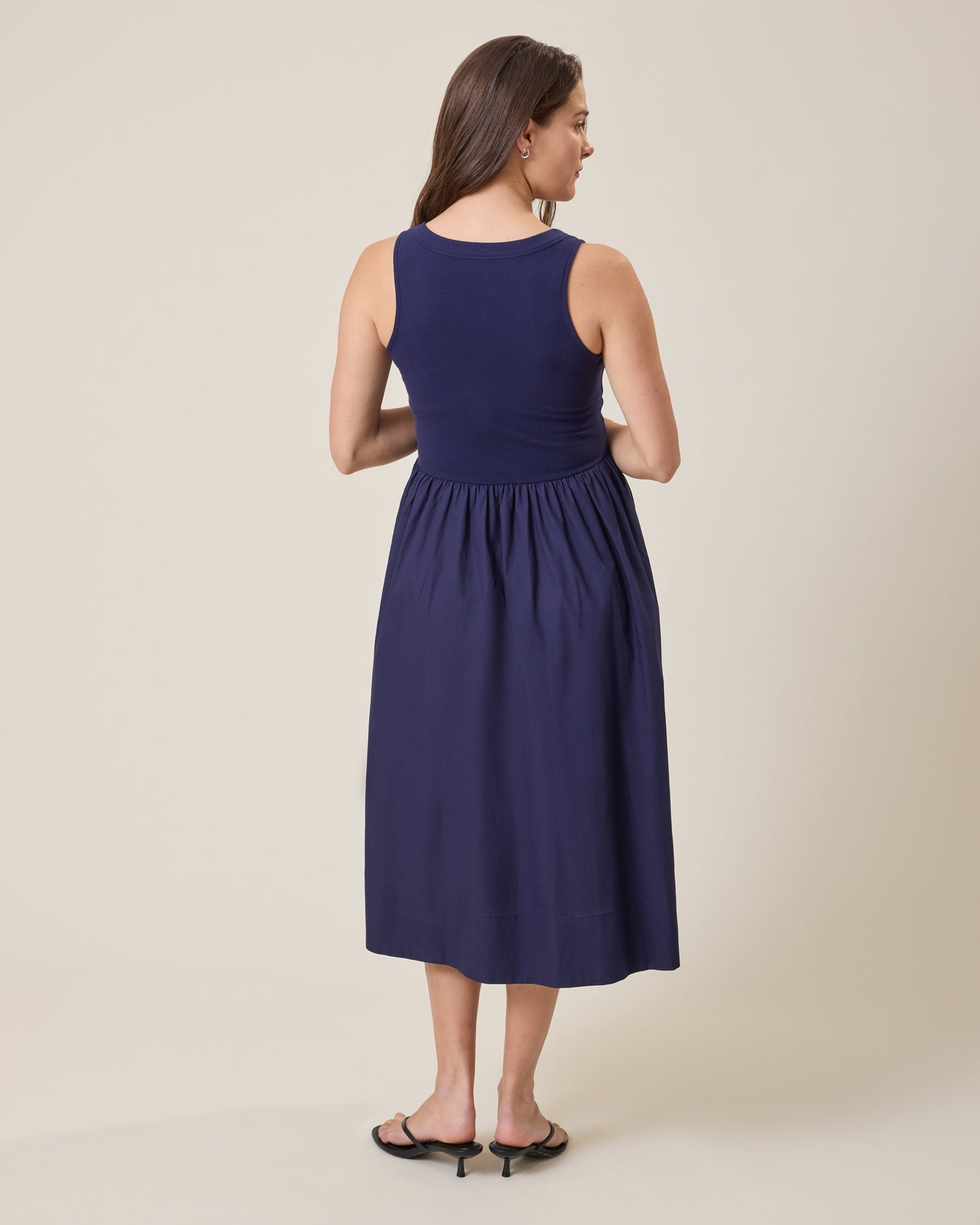 Woman wearing Charlotte Mixed Media Nursing Midi Dress in navy against a beige background