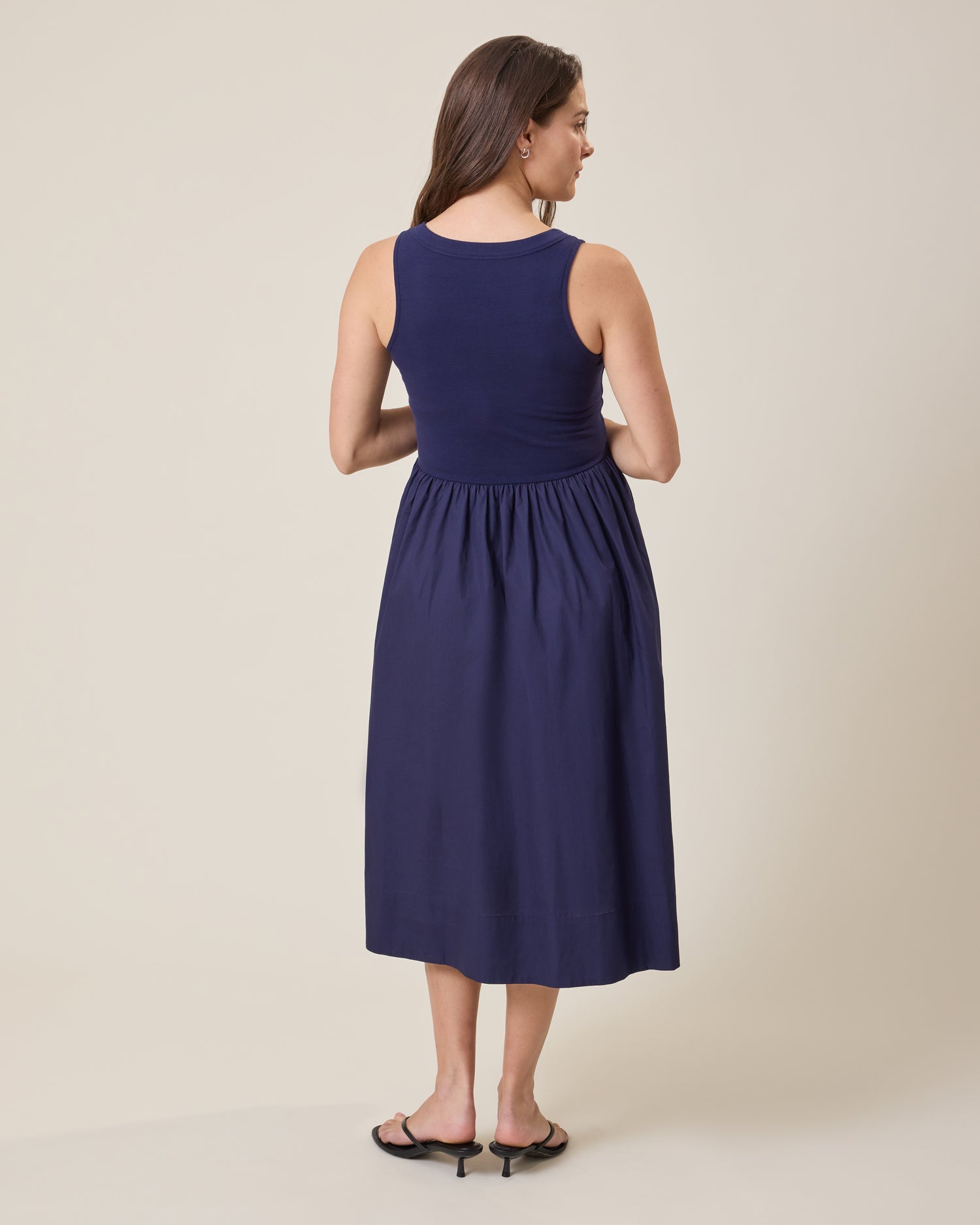 Woman wearing Charlotte Mixed Media Nursing Midi Dress in navy against a beige background
