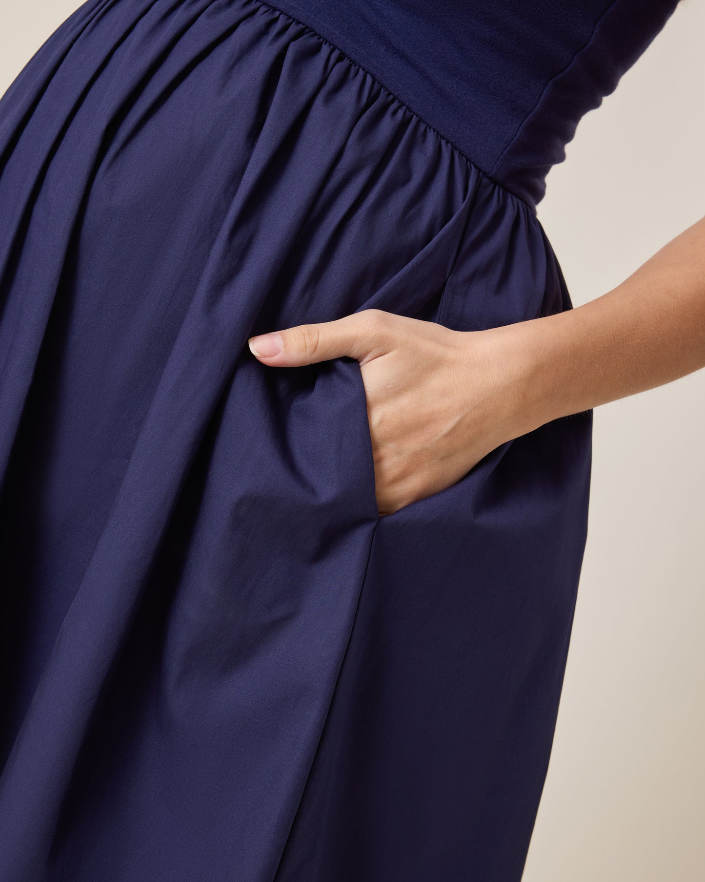 Charlotte Mixed Media Nursing Midi Dress in navy with a hand adjusting the fabric on a neutral background