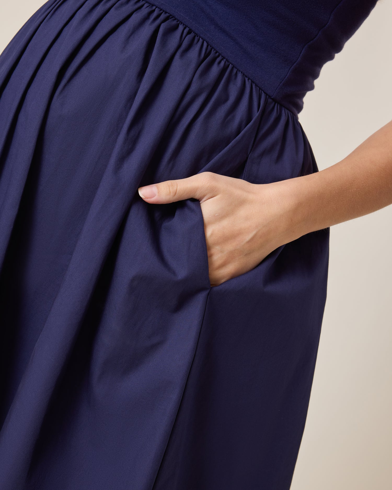 Charlotte Mixed Media Nursing Midi Dress in navy with a hand adjusting the fabric on a neutral background