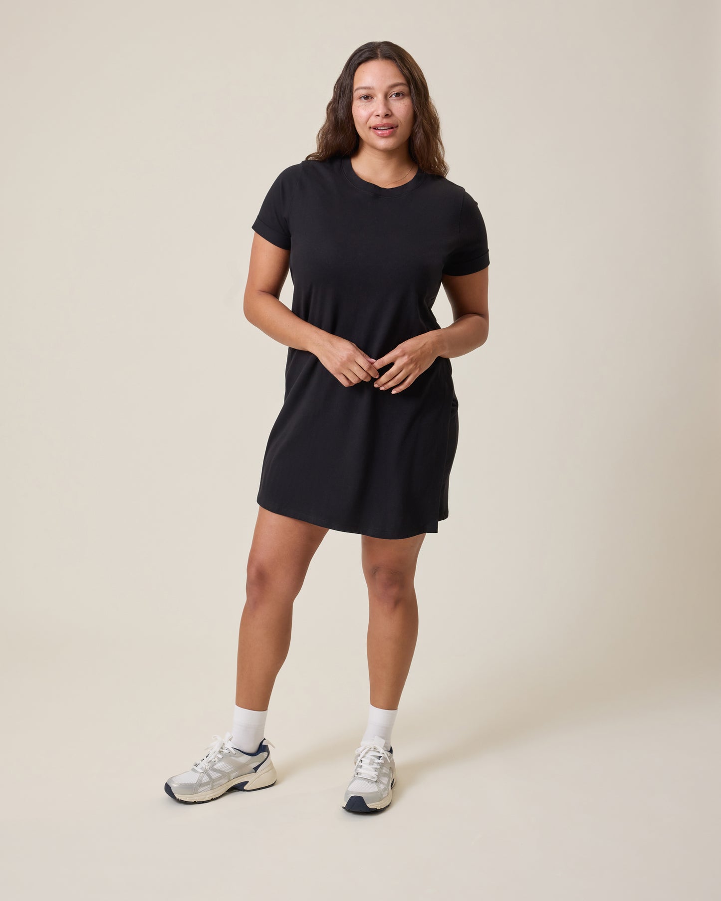 Woman wearing the Classic Nursing T-shirt Mini Dress in black on a beige background@model_info:Alana is 5'7" and wearing a Large.