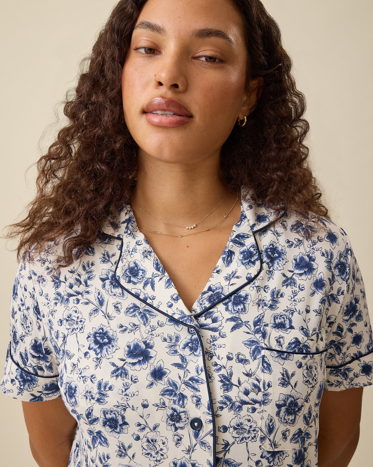 Woman wearing a blue floral pajama top with a neutral background