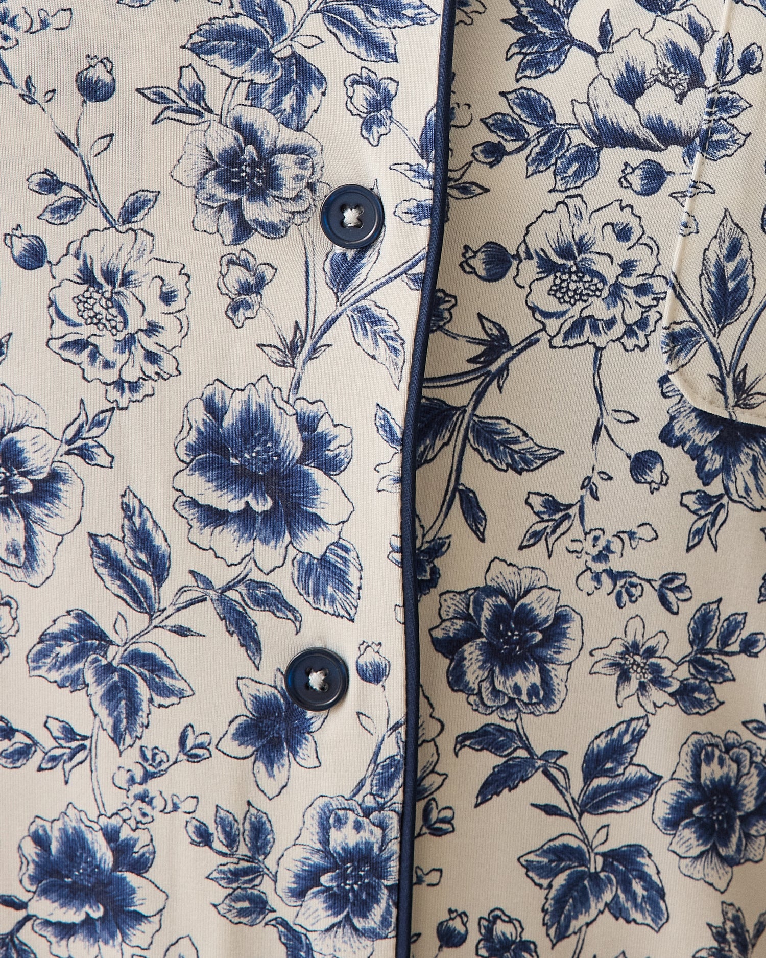Close-up of navy toile pattern, a floral patterned fabric with blue flowers on a beige background.