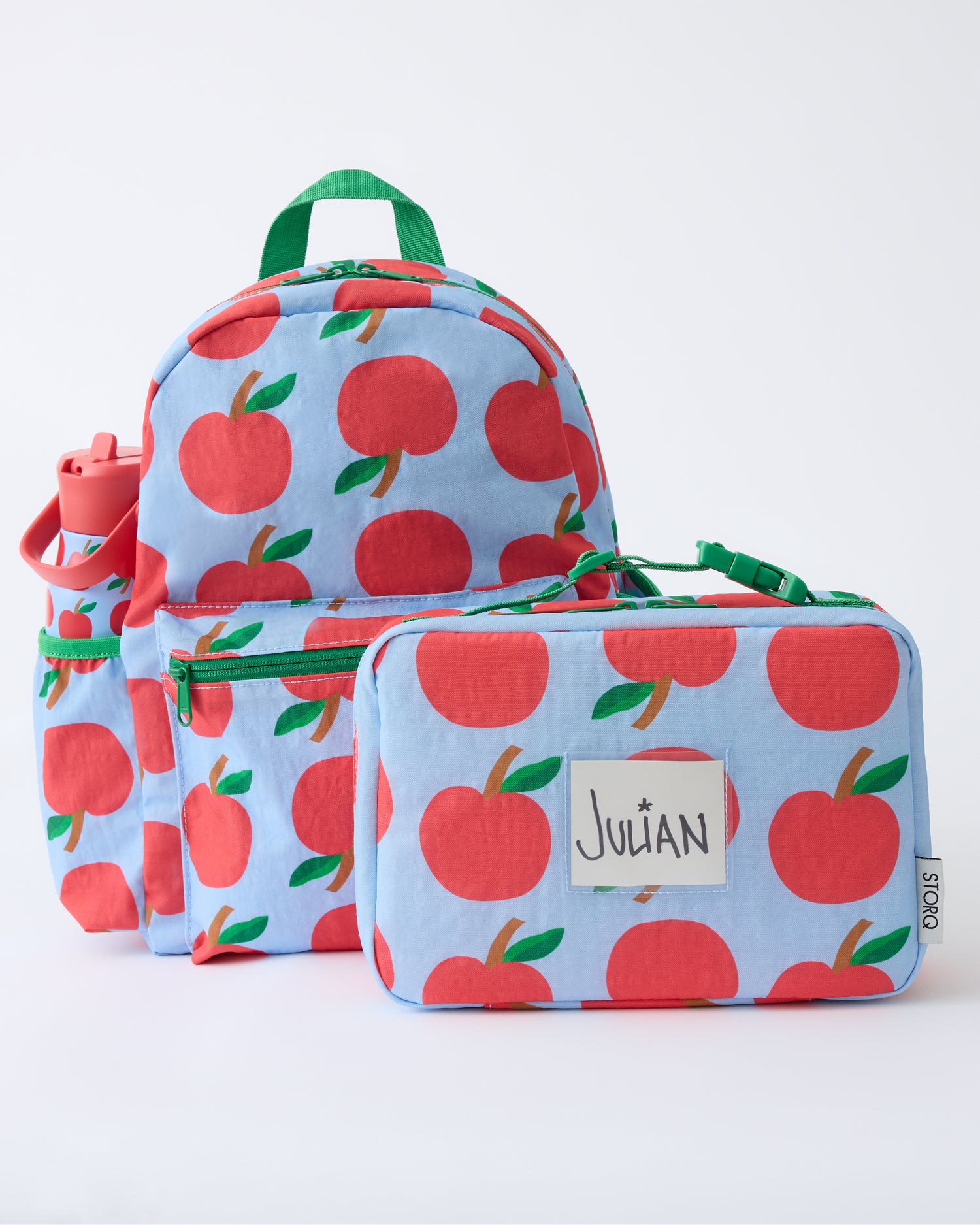 The Cool Kid Backpack, Water Bottle and Lunch Box in Blue Apple on a beige background.