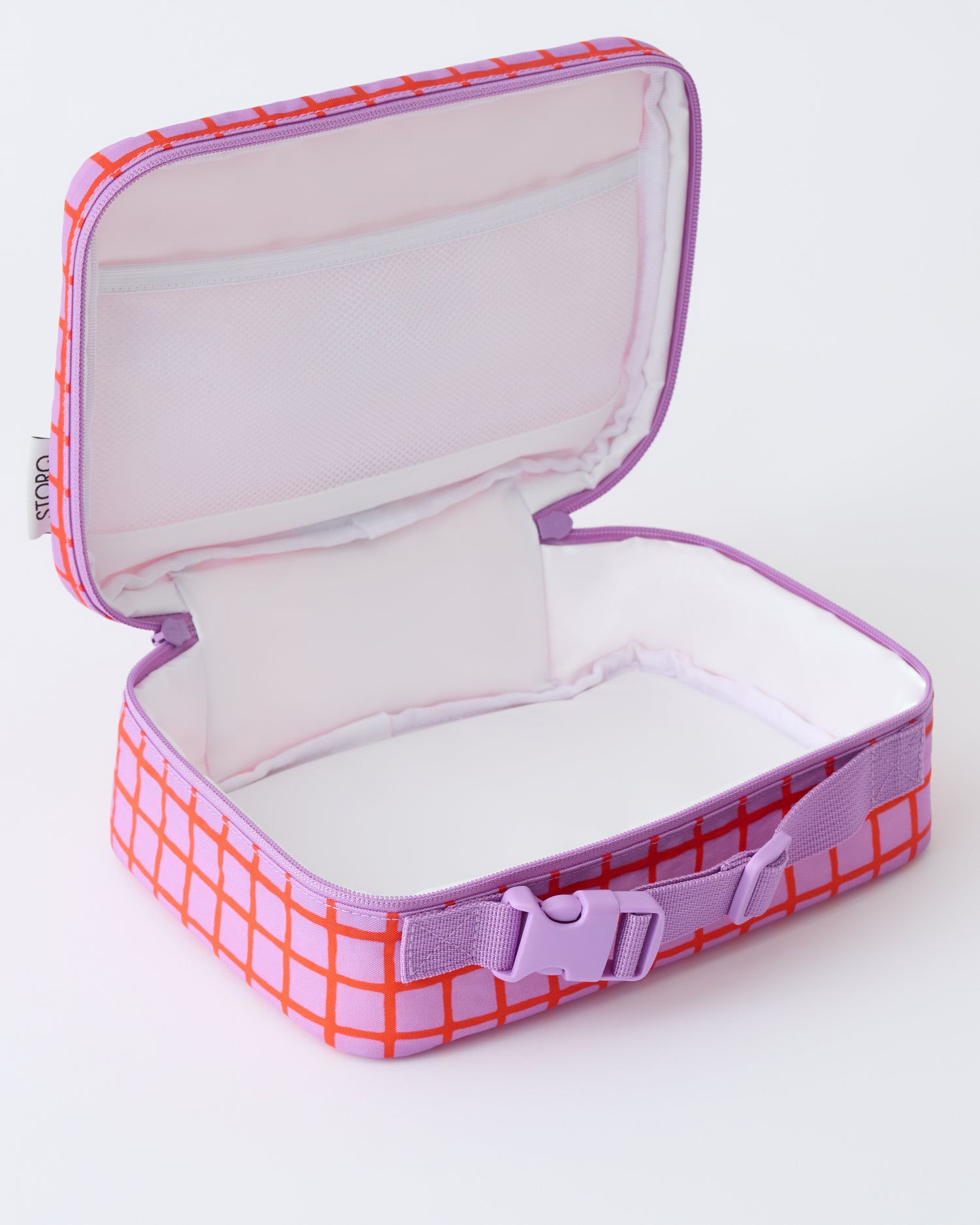 Angled view of opened Cool Kid Lunch Box in Orchid Grid, showing space and pocket, on a beige background.