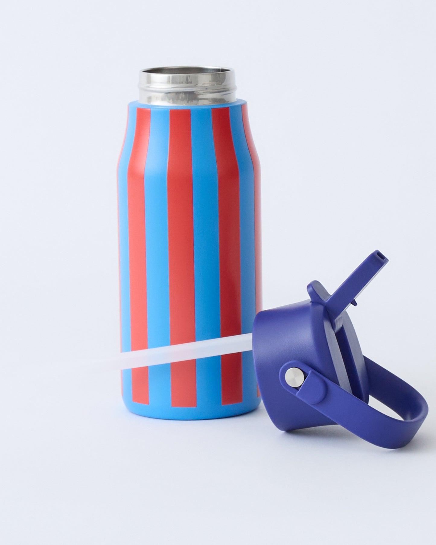 Cool Kid Water Bottle in Blue & Rust Stripe with lid off, laying with straw in front, on beige background.