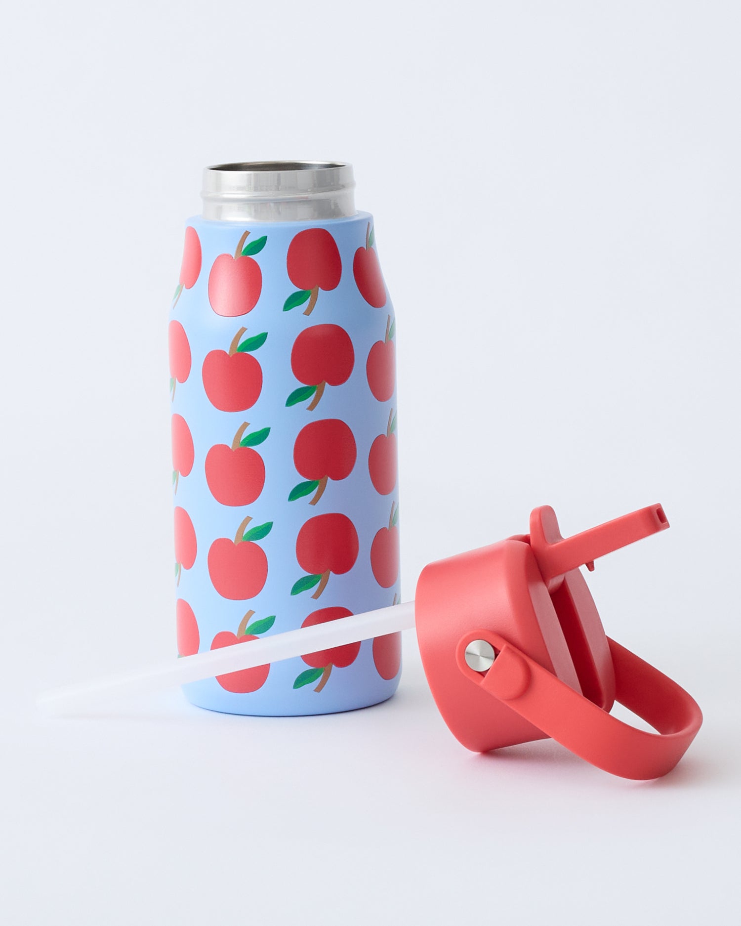 Cool Kid Water Bottle in Blue Apple with lid off, laying with straw in front, on beige background.