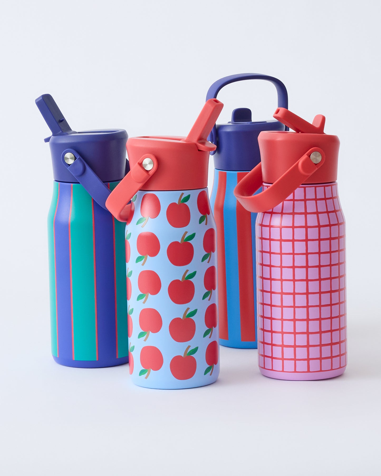 All four Cool Kid Water Bottles, in Orchid Grid, Blue Apple, Blue & Rust Stripe, and Navy & Green Stripe, on a beige background.