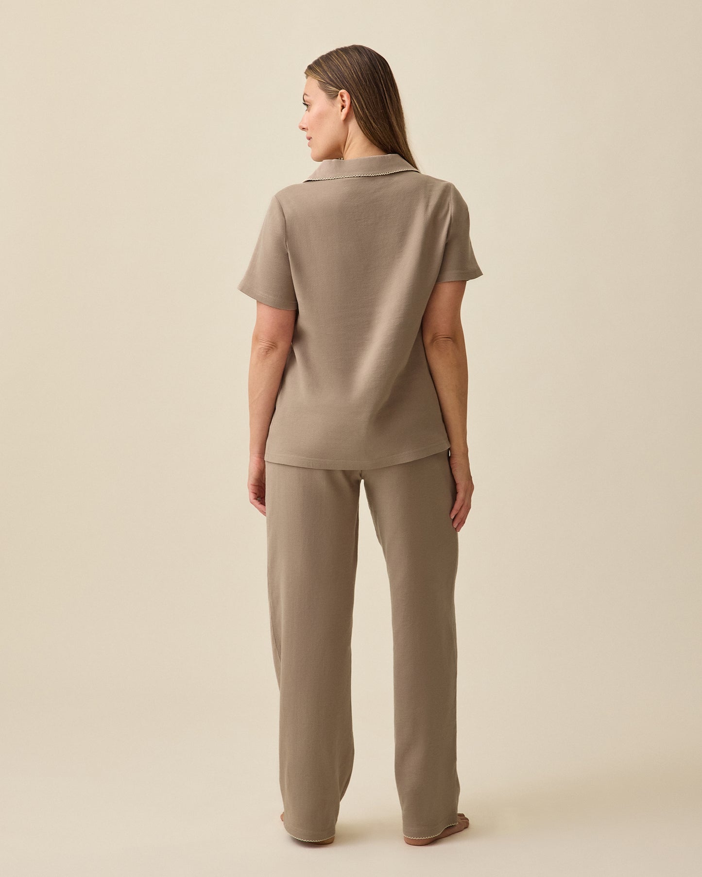 Back view of Model wearing Cotton Bamboo Pajama Set in Taupe on a beige background. 