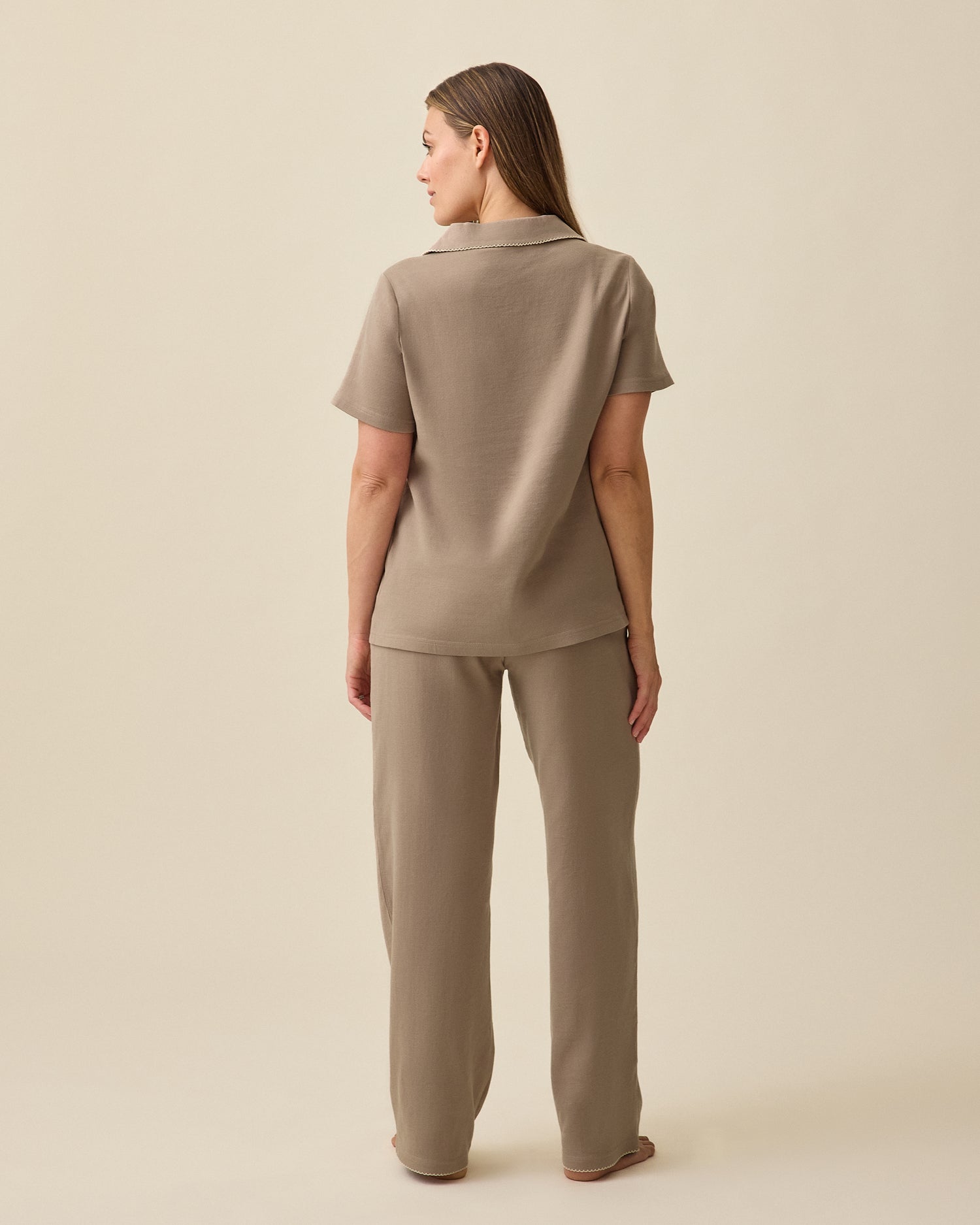 Back view of Model wearing Cotton Bamboo Pajama Set in Taupe on a beige background. 