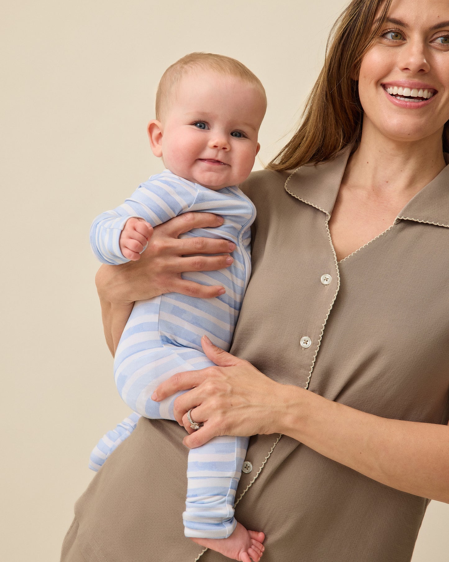 Woman holding baby while wearing Cotton Bamboo Pajama Set in Taupe on a beige background. Baby is wearing Bamboo Baby Pajama in Blue Watercolor.
