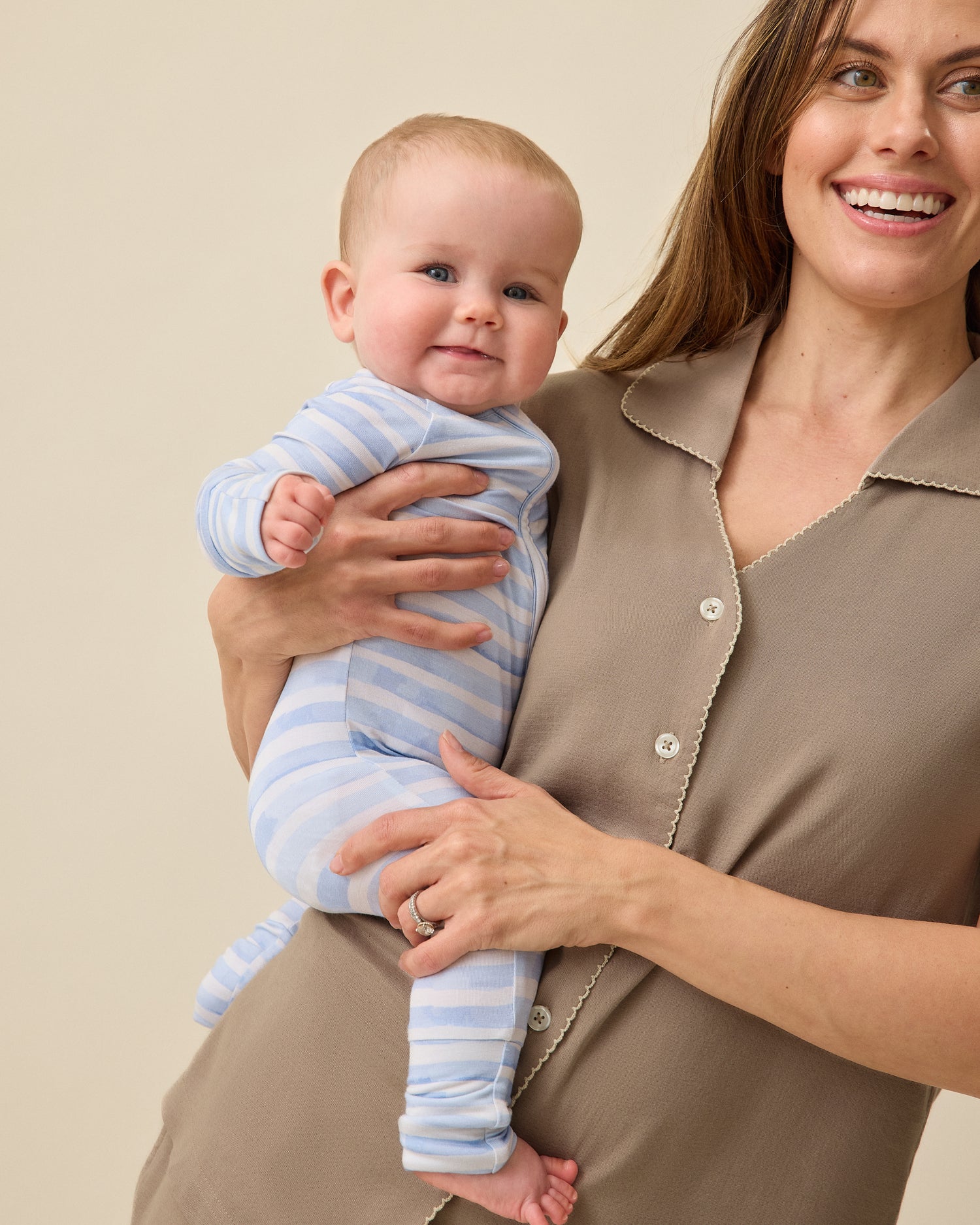 Woman holding baby while wearing Cotton Bamboo Pajama Set in Taupe on a beige background. Baby is wearing Bamboo Baby Pajama in Blue Watercolor.