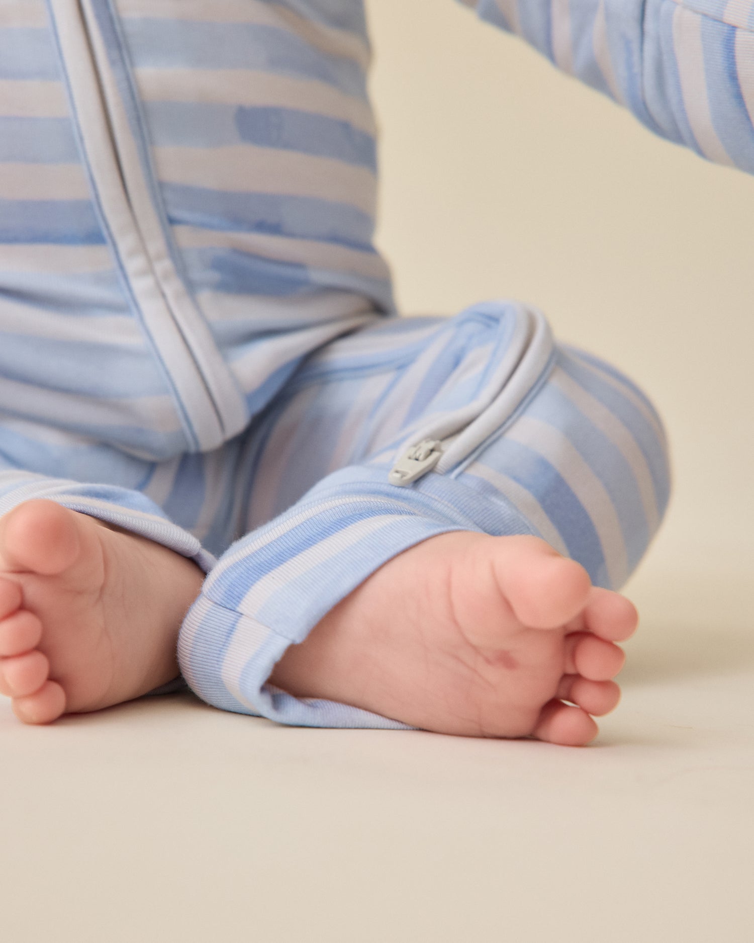 Baby's feet in baby wearing the Bamboo Baby Pajama in Blue Watercolor on a light background