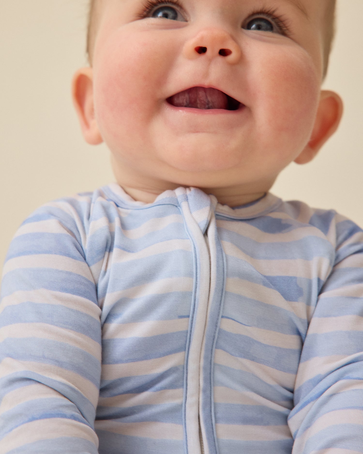 Close-up of baby wearing the Bamboo Baby Pajama in Blue Watercolor on a plan background