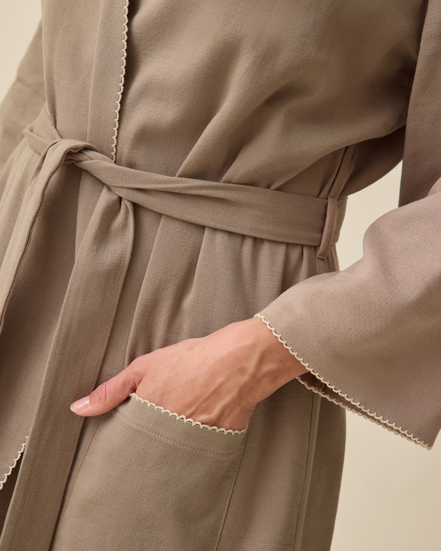 Model using pockets on Cotton Bamboo Robe in Taupe on a beige background