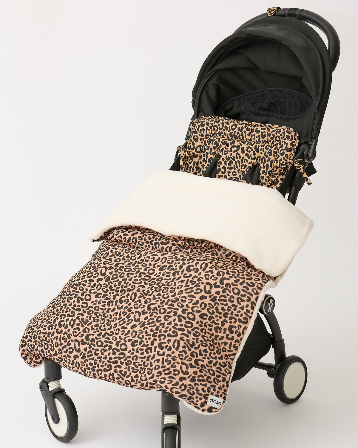 Cozy Stroller Blanket in Leopard and Stroller Party™ Seat Liner & Strap Covers in Leopard on a black stroller, on an off white background.