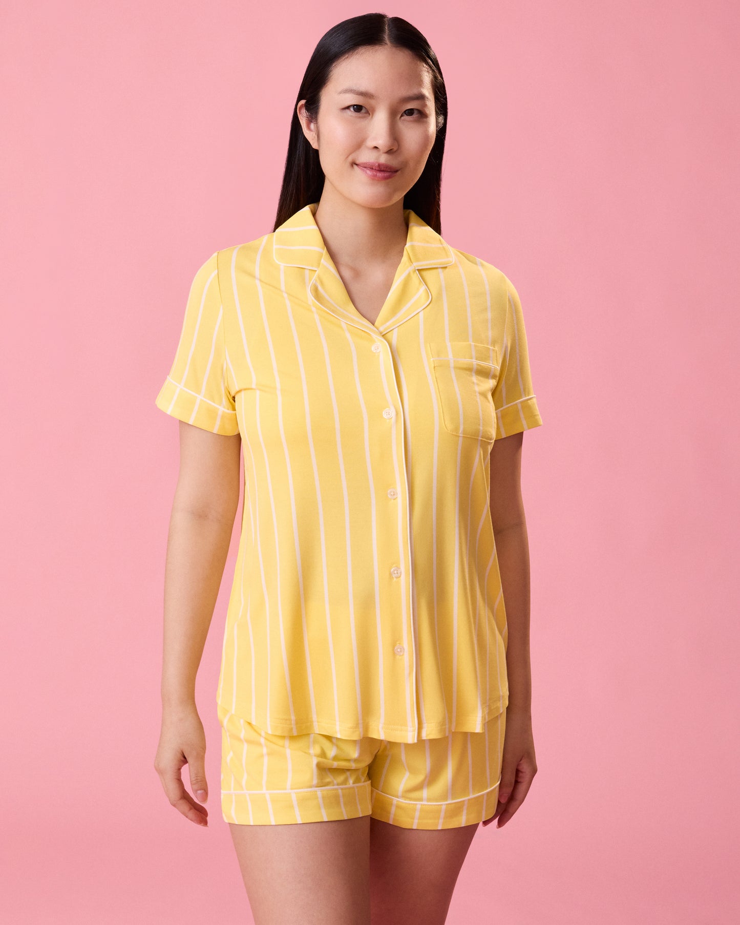 Front view of model wearing Clea Bamboo Short Sleeve Pajama Set in Dandelion Stripe on a pink background@model_info:Cassie is 5'9" and wearing a Small.