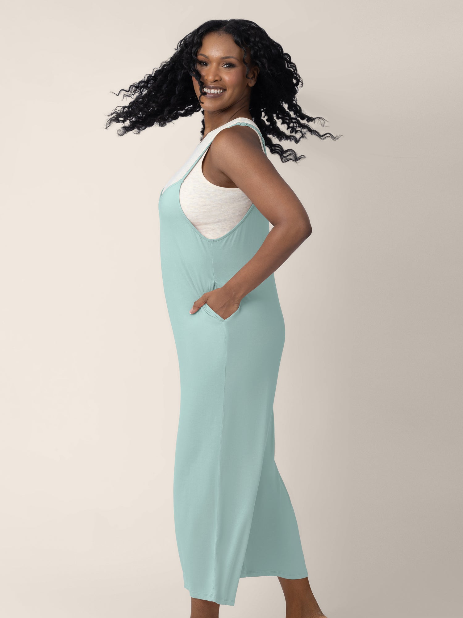A side view of a model wearing the Charlie Maternity & Nursing Romper in Dusty Blue Green.