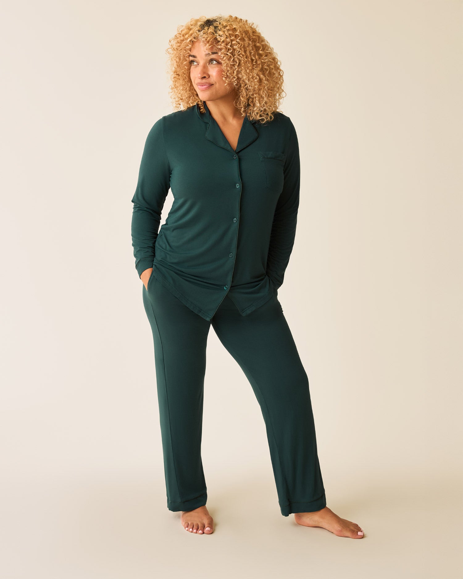 Woman wearing the Clea Bamboo Long Sleeve Pajama Set in Evergreen with hands in pockets