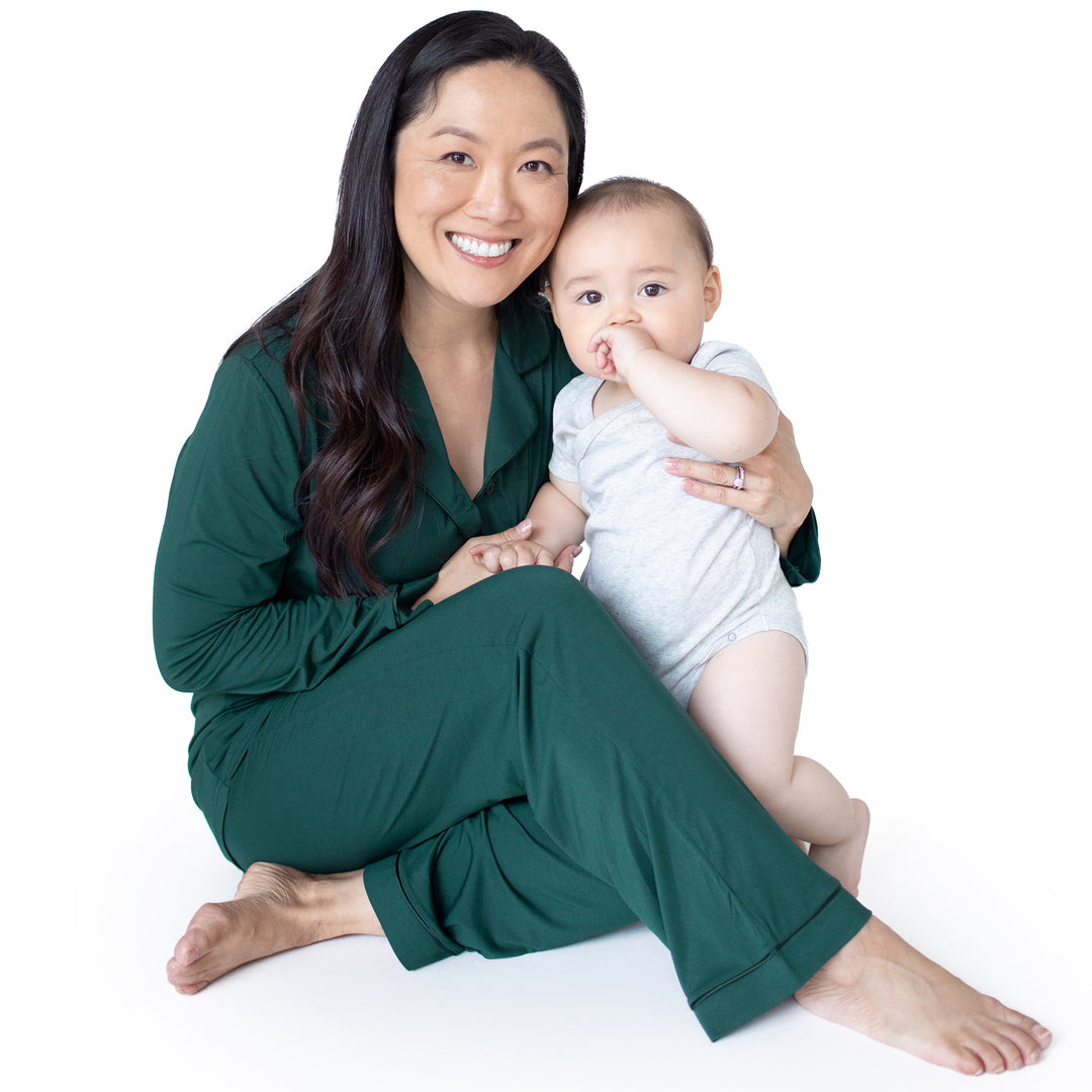 Model smiling at the camera with her baby wearing the Clea Bamboo Long Sleeve Pajama Set in Evergreen