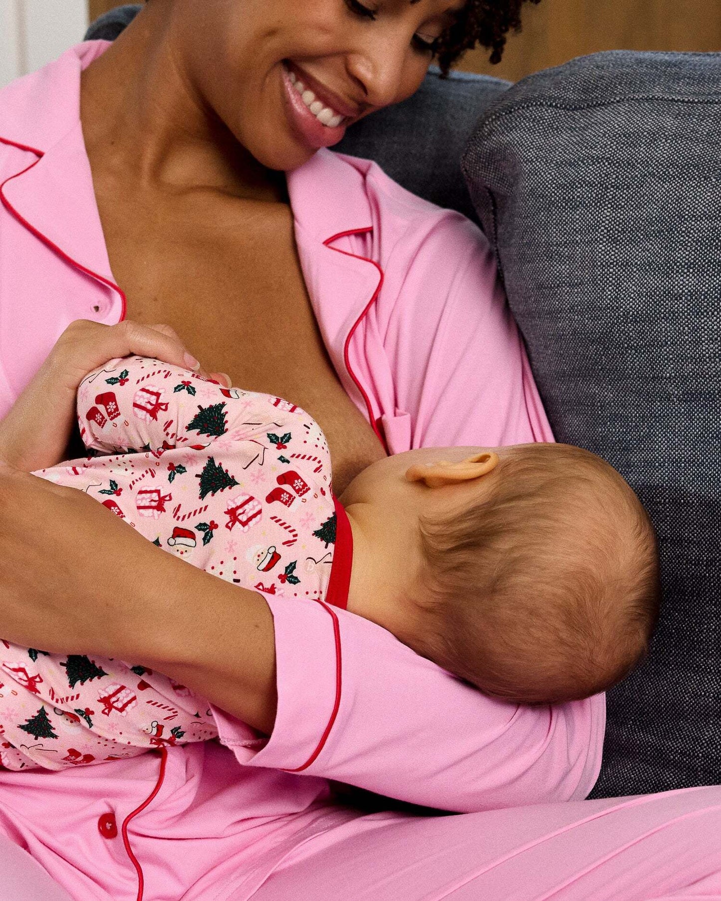 Woman in pink pajamas holding a baby in a matching outfit.