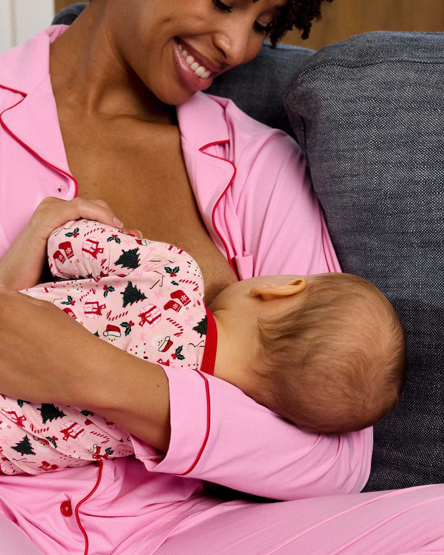 Woman in pink pajamas holding a baby in a matching outfit.
