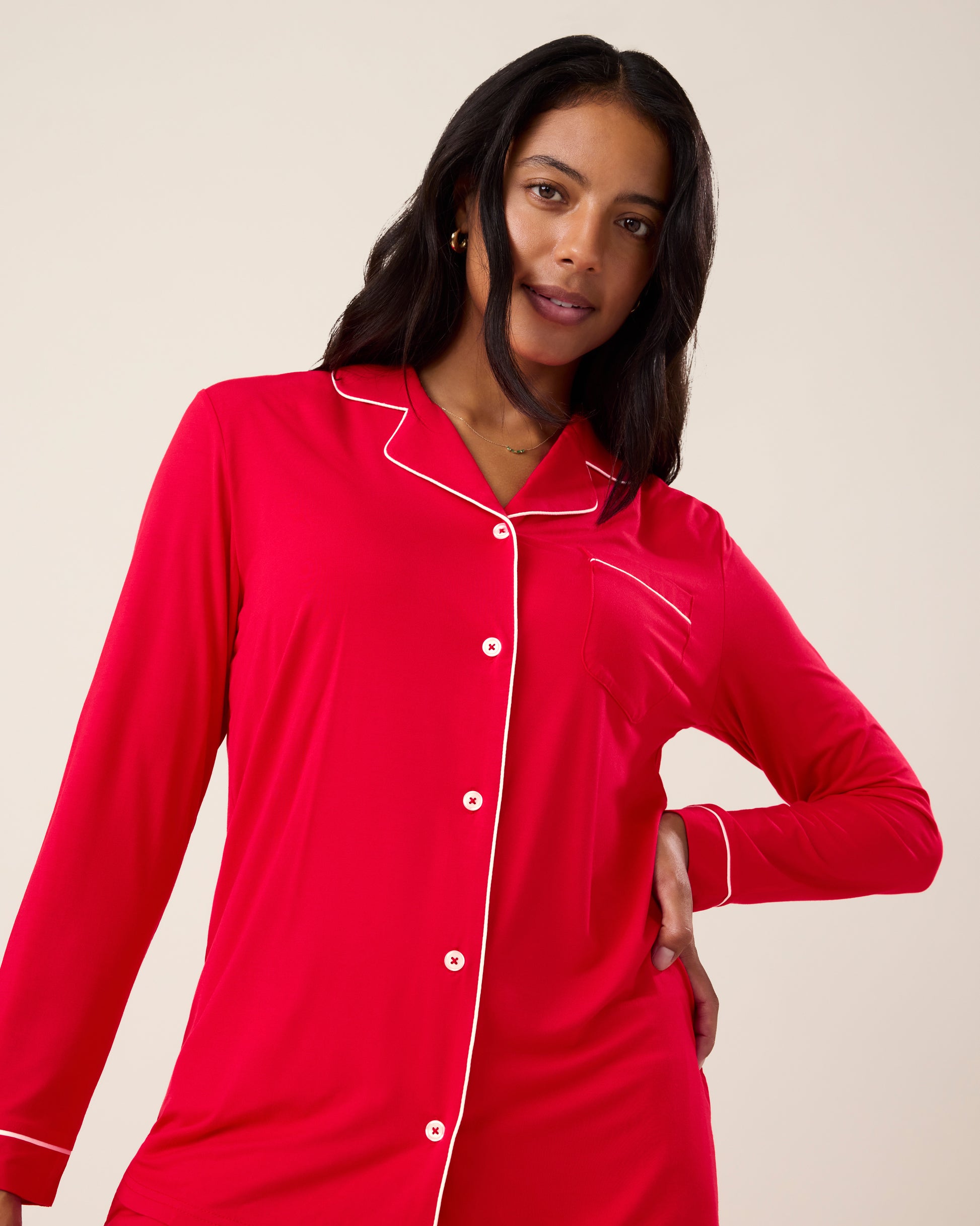 Woman wearing the Clea Bamboo Long Sleeve Pajama Set in Red, with white piping