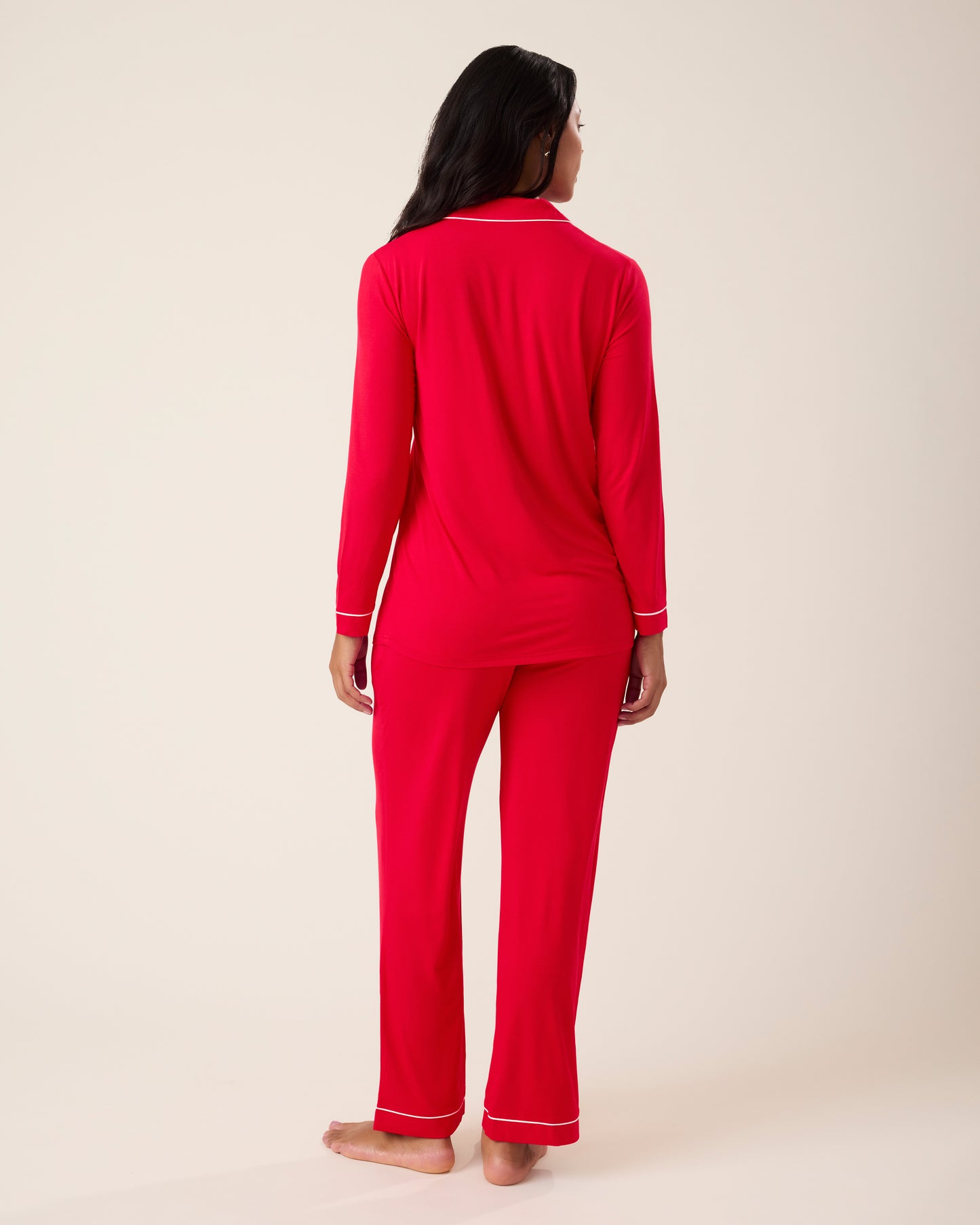 Woman wearing the Clea Bamboo Long Sleeve Pajama Set in Red, with white piping