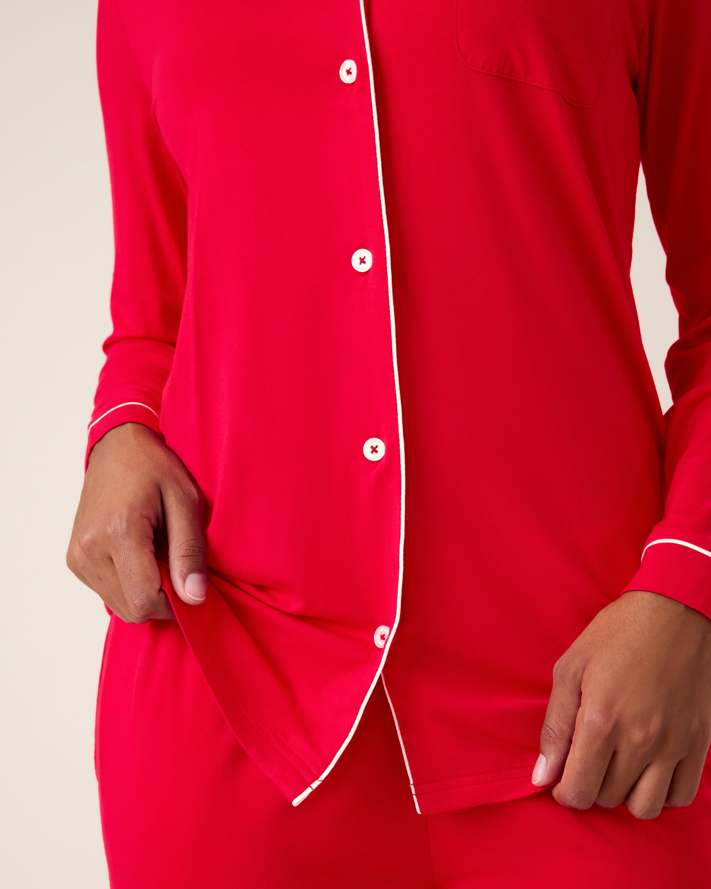 Woman wearing the Clea Bamboo Long Sleeve Pajama Set in Red, with white piping showing white buttons