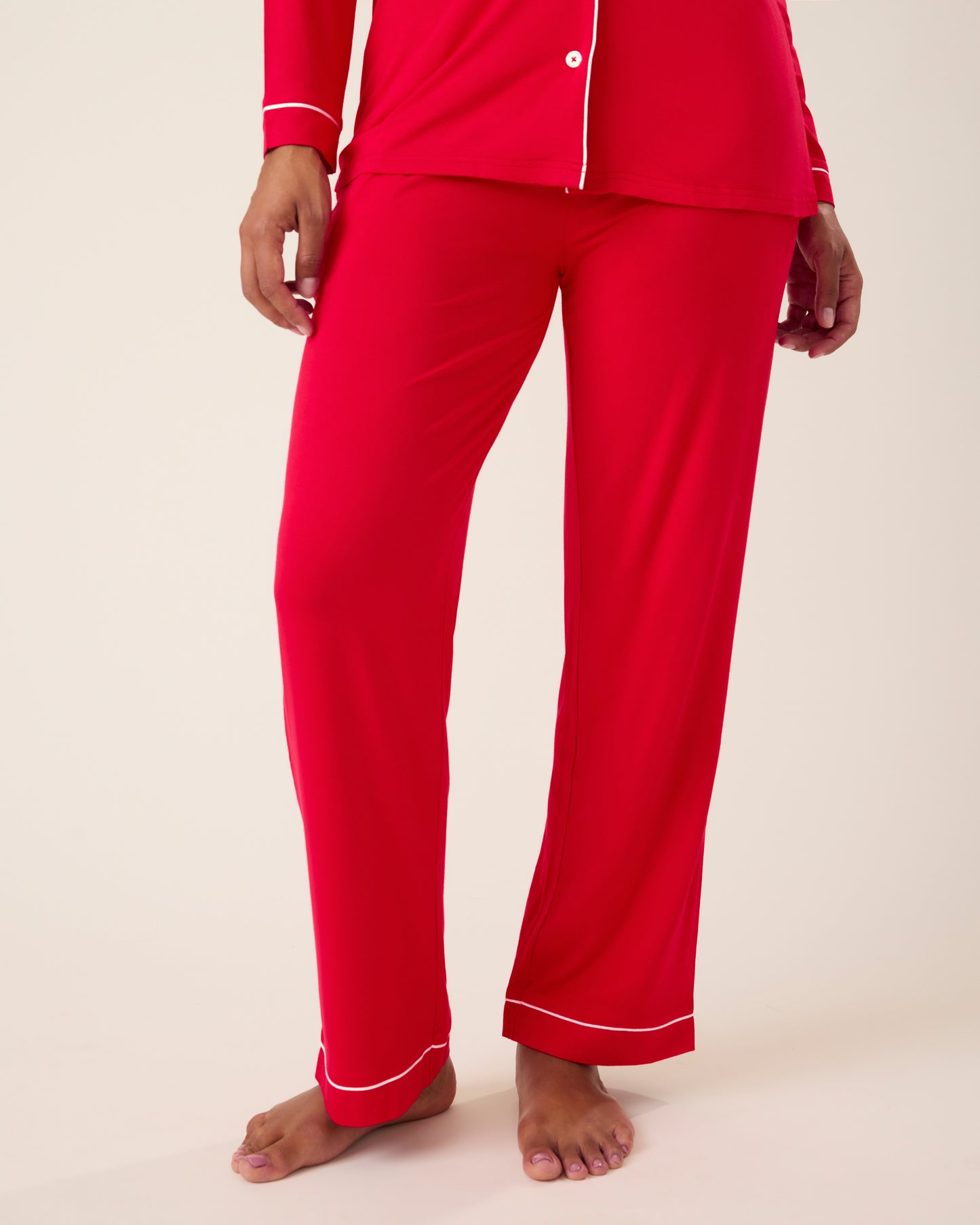 Woman wearing the Clea Bamboo Long Sleeve Pajama Set in Red with white piping, focused on bottoms