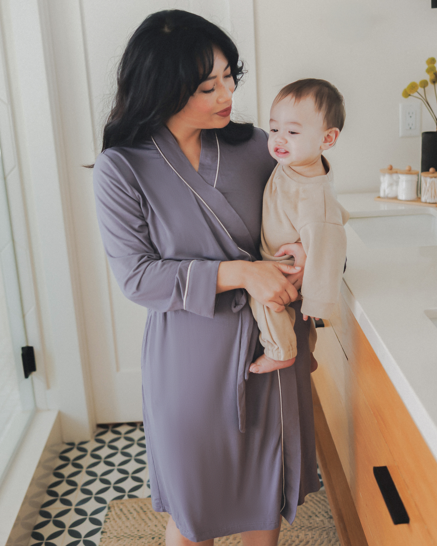 Model wearing the Clea Bamboo Robe in Granite while holding her baby on her hip @model_info:Nikki is wearing a S/M.