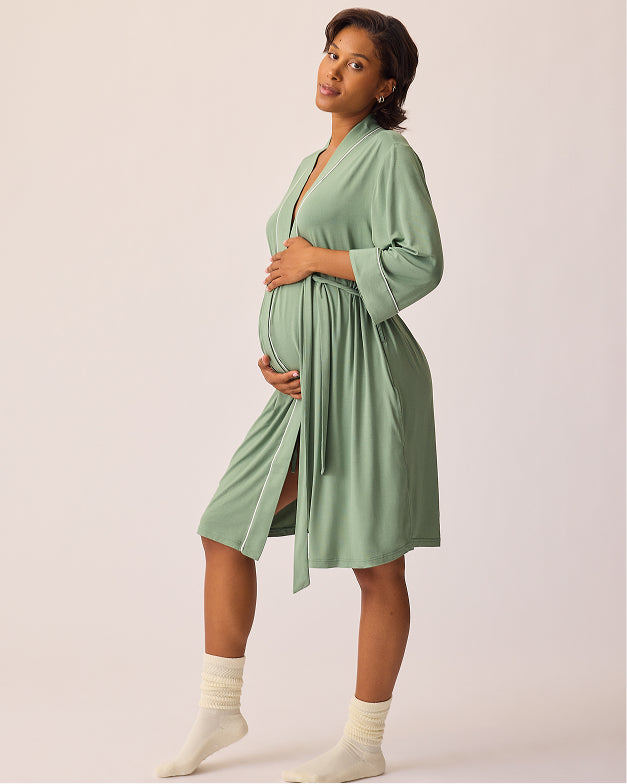 A pregnant woman wearing a sage green silk-like maternity robe with three-quarter sleeves and a self-tie waist, standing against a solid light beige studio background. @model_info:Ale is 5'9" and wearing a S/M.