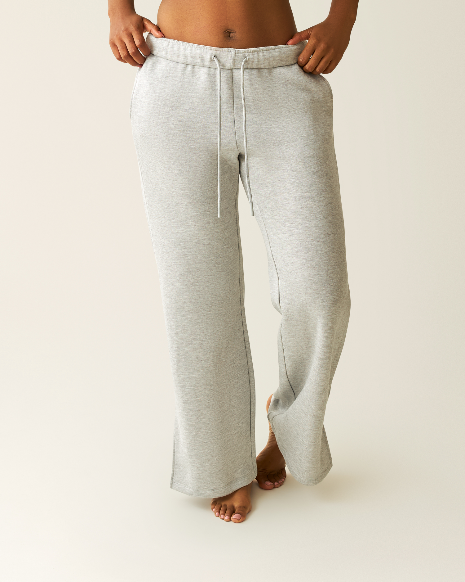 Woman wearing heather grey Cloud Fleece Sweatpant on a beige background@model_info:Kyra is 5'9" and wearing a Small.