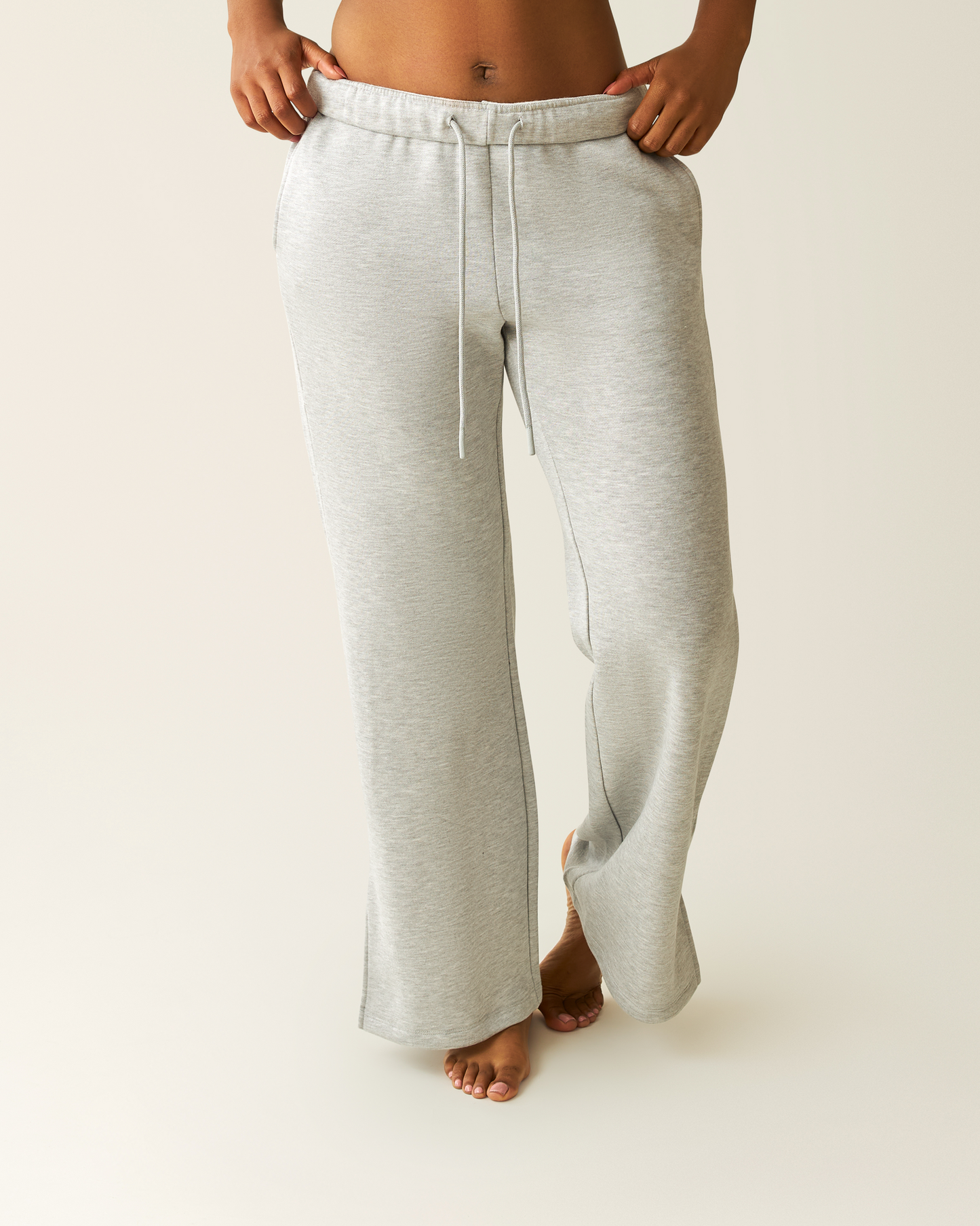 Woman wearing heather grey Cloud Fleece Sweatpant on a beige background